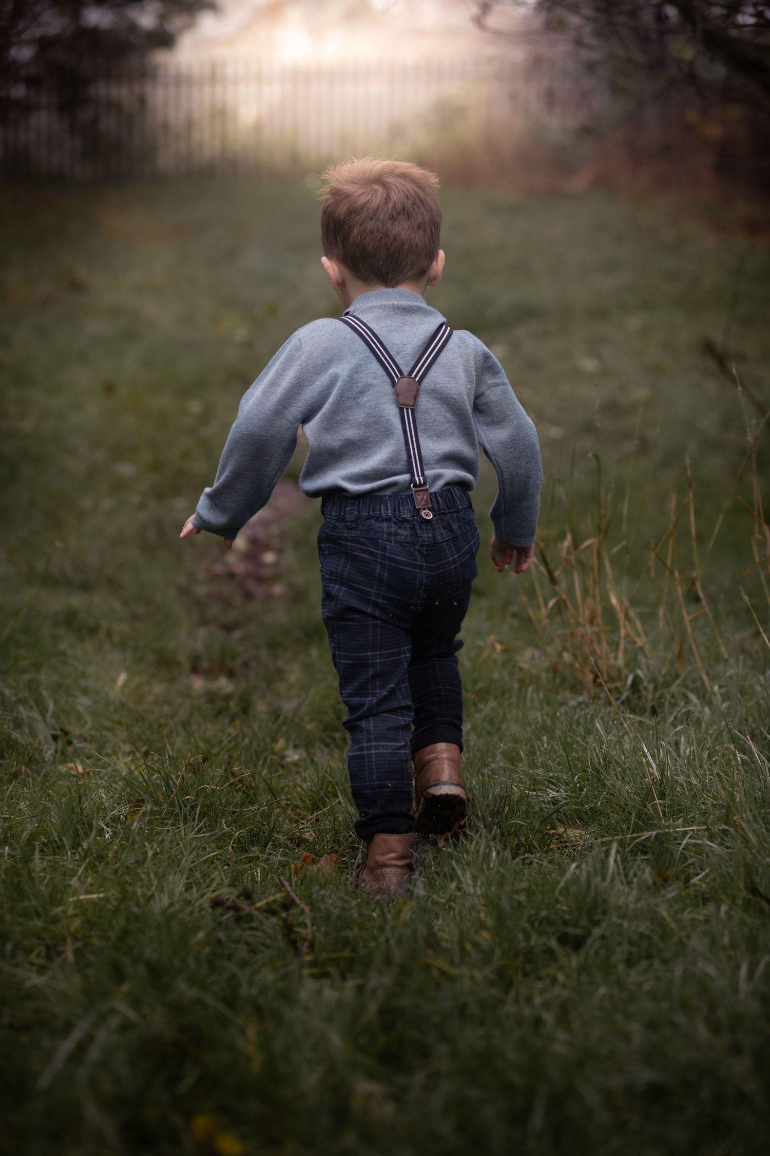 Toddler boy in suspenders and boots walking away on a grassy garden path.

Stone Village Hull