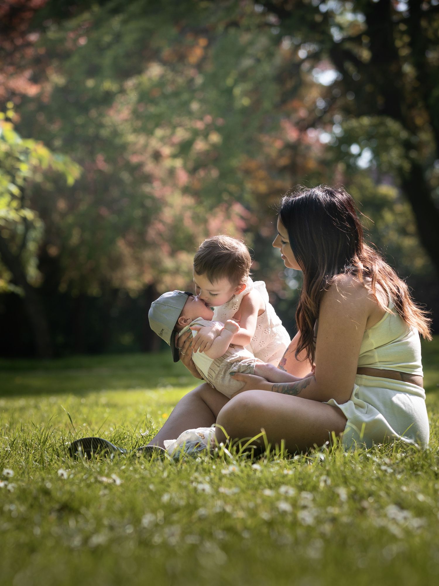 Young mother sitting on grass cradling her baby in a sunny green park.

East Park Hull
