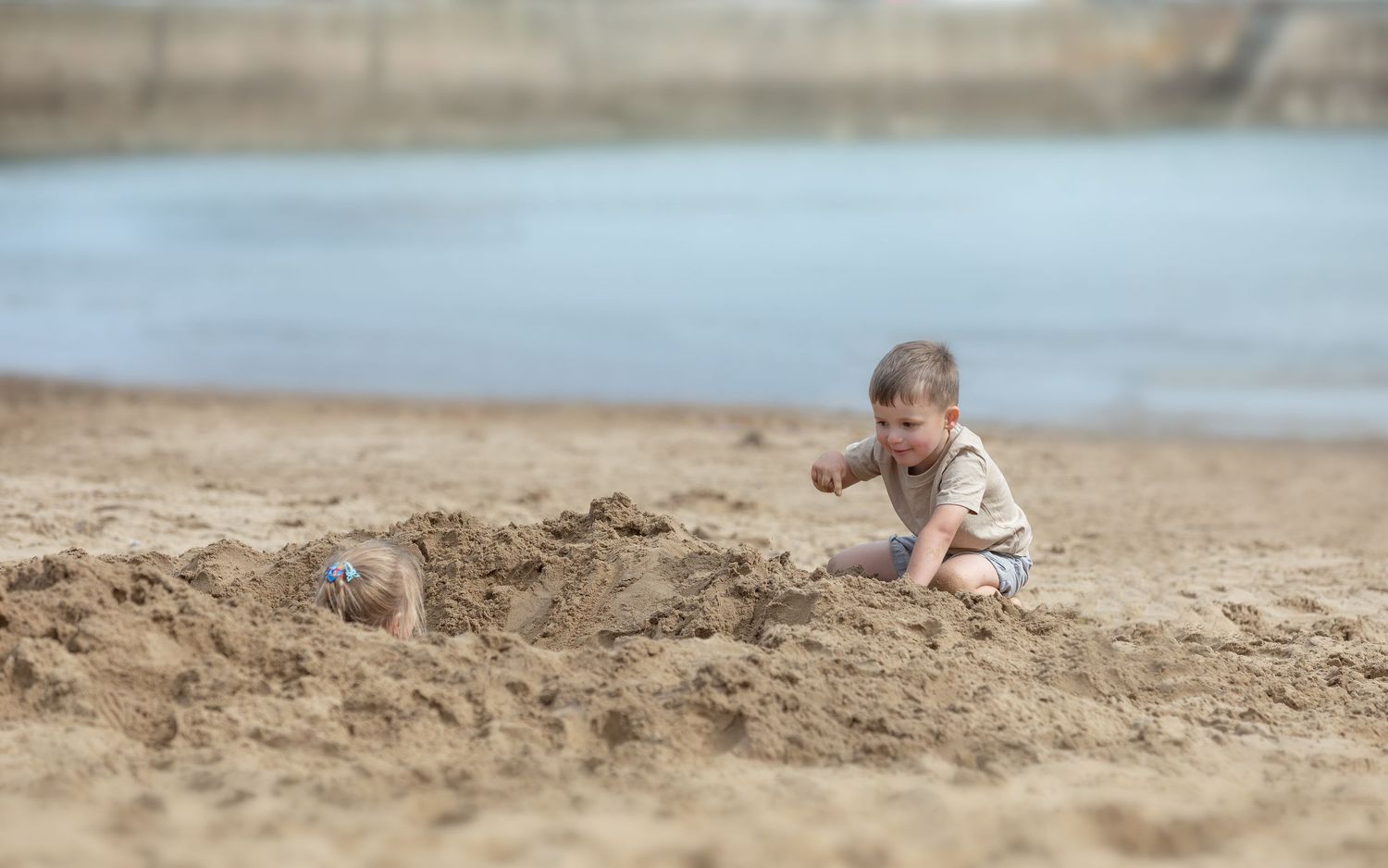 A curious toddler plays and digs in the sand on a beach near the water's edge on a calm day.

Scarborough