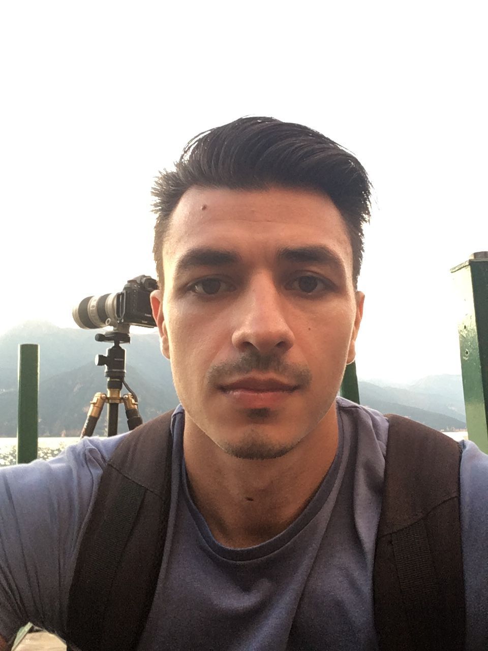 Young man taking a selfie outdoors with a camera on a tripod behind him.

Metsovo Greece