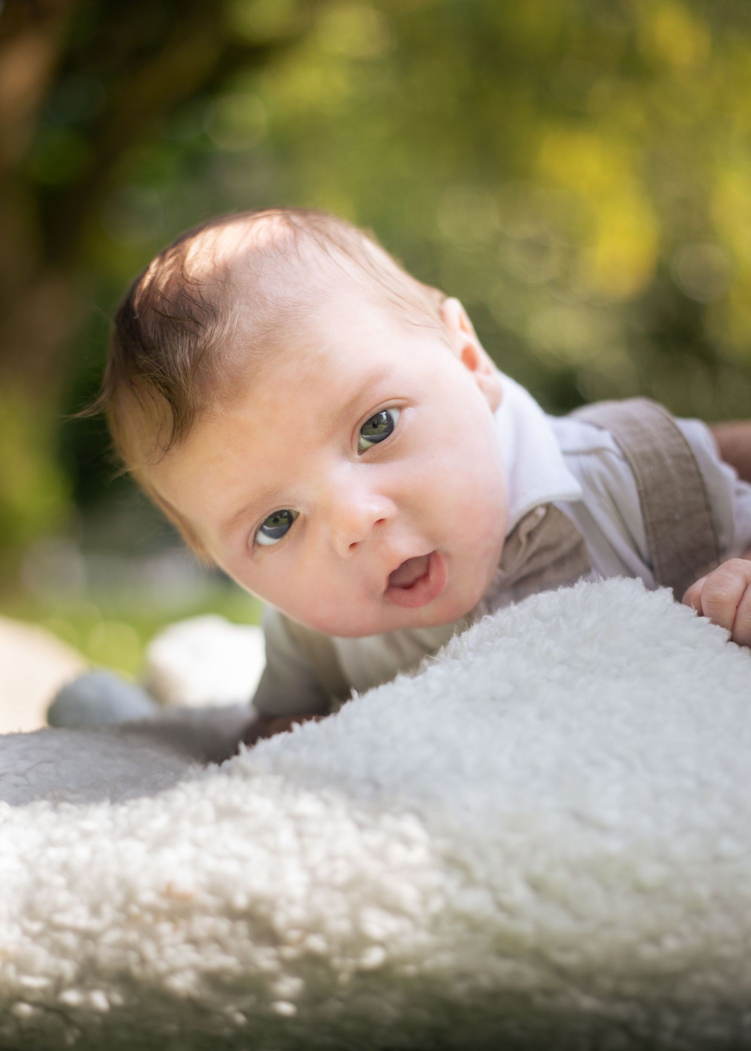 Adorable baby with blue eyes doing tummy time on fluffy white blanket in sunny garden setting.

East Park Hull