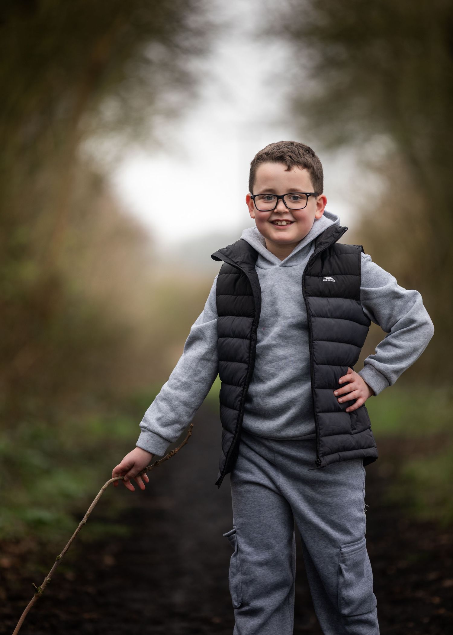 Smiling boy in glasses holding a stick on a woodland path.

Keyingham