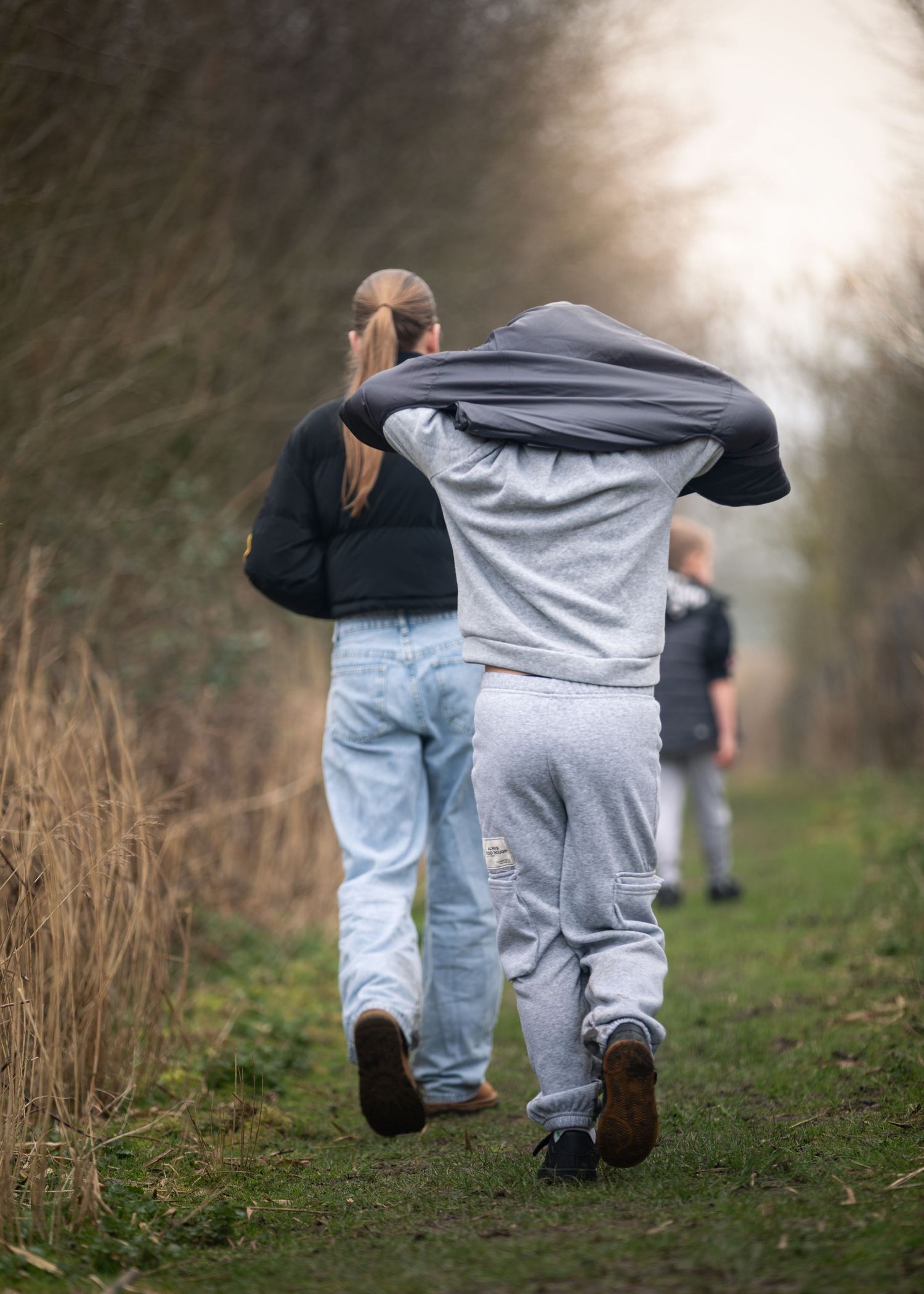Couple walking arm in arm along rural woodland path with child following behind in winter.

Keyingham