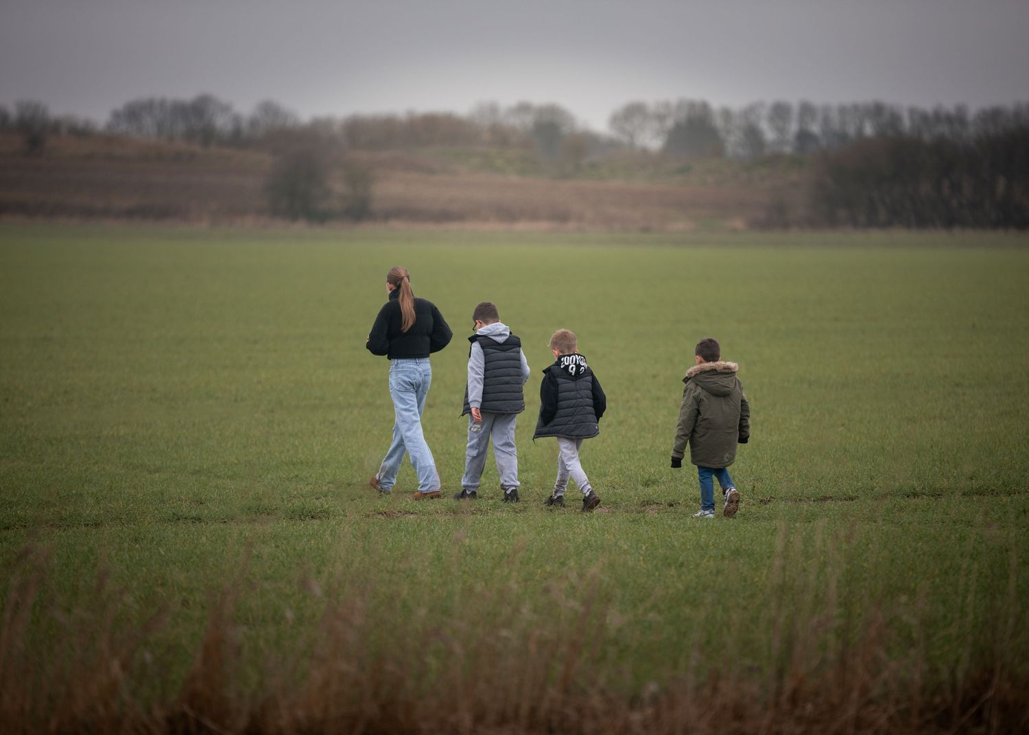 Four people walking through a lush green field on an overcast day in the countryside. Keyingham