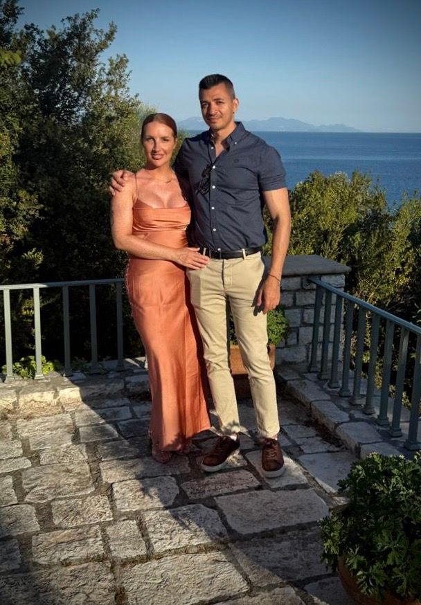 Smiling couple posing together on a stone terrace overlooking a scenic coastal view.

Corfu Greece
