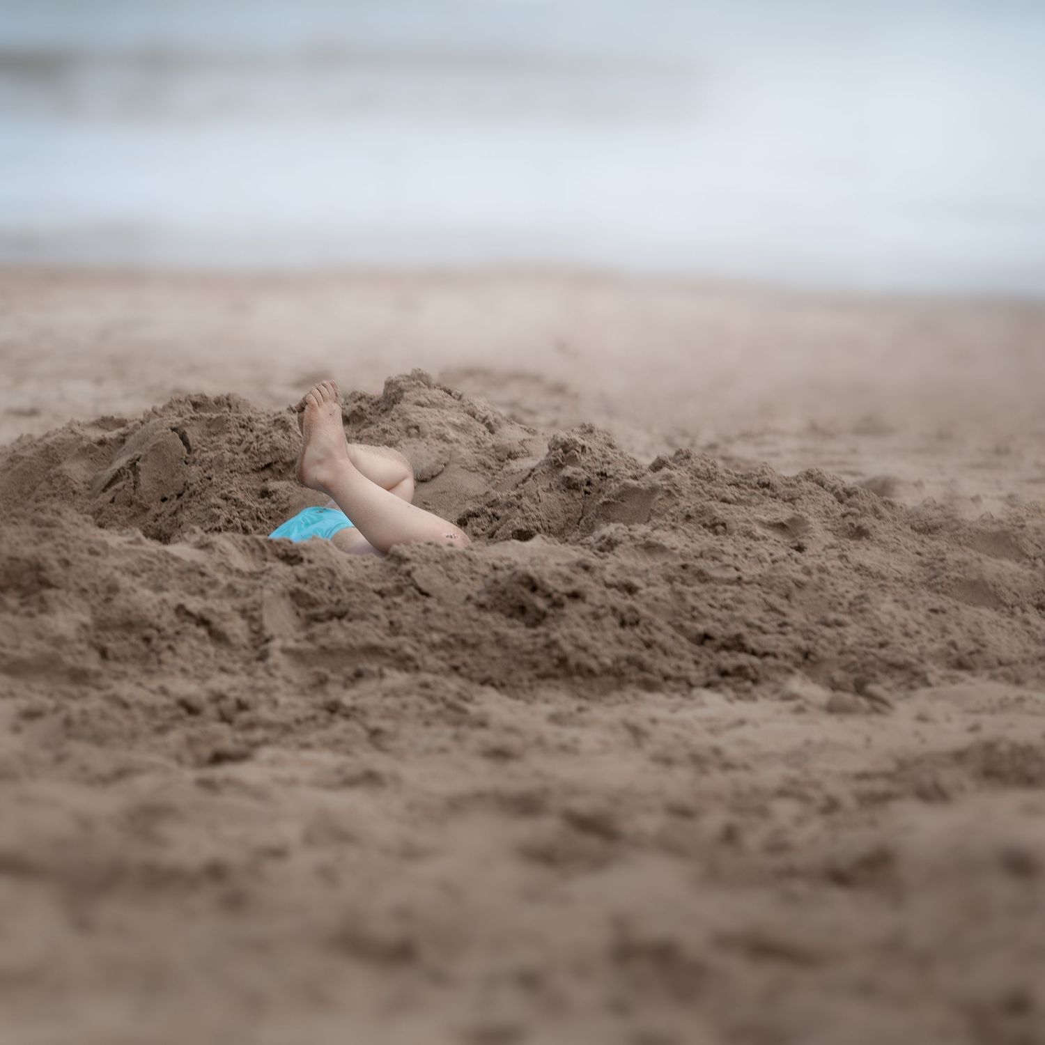 Child's legs buried in sand at the beach with a blue shovel nearby.

Scarborough