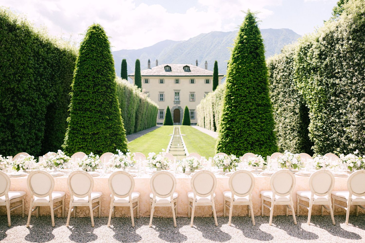 Elegant outdoor wedding reception at an Italian villa with long tables and manicured hedges.