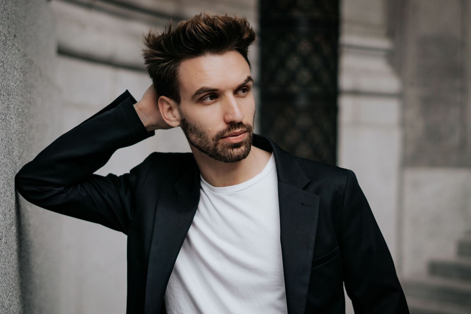 A person in a black blazer and white t-shirt poses against a light background in a series of professional portraits.