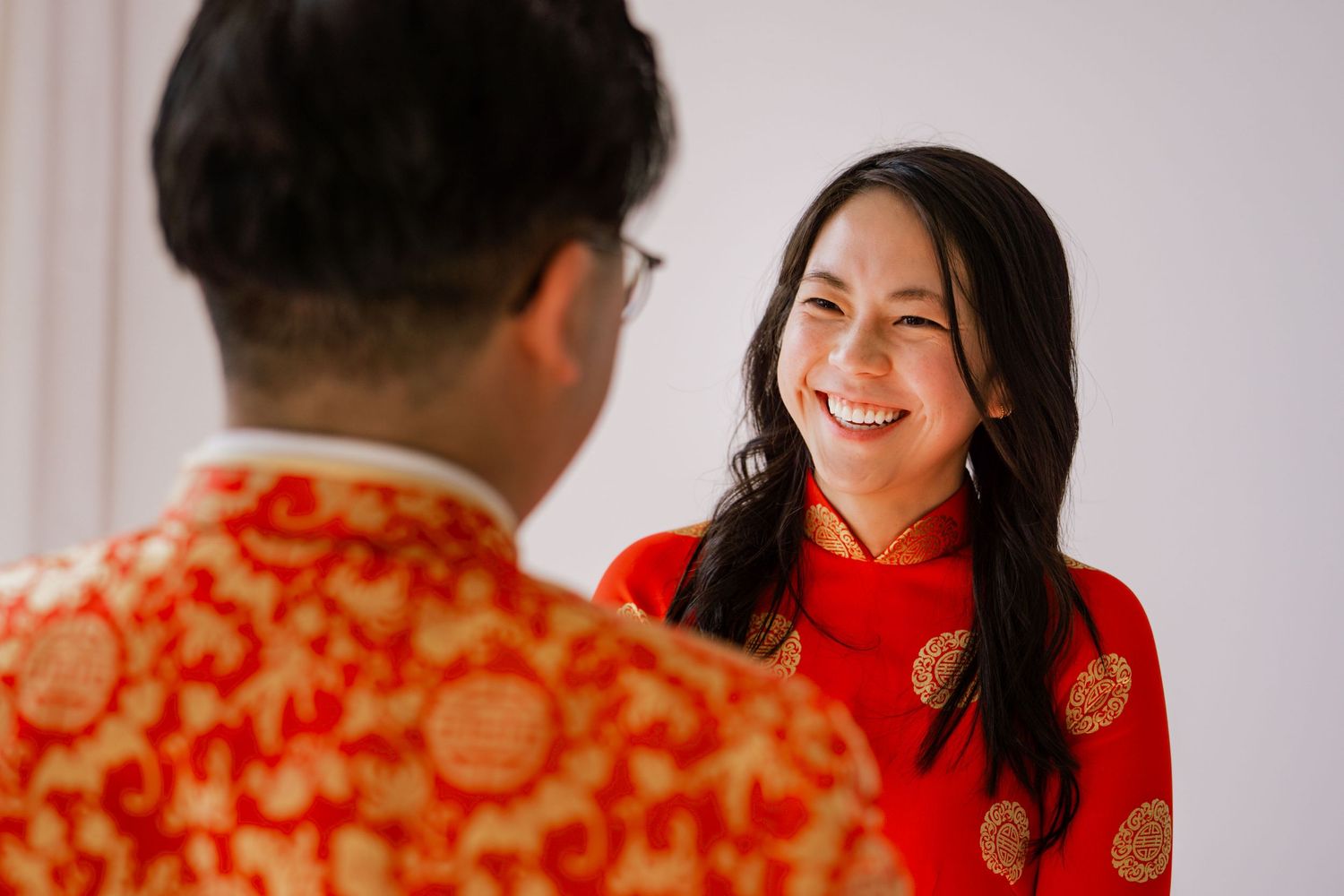 A couple in traditional red Chinese qipao dress and formal wear smiling and celebrating a special occasion together.