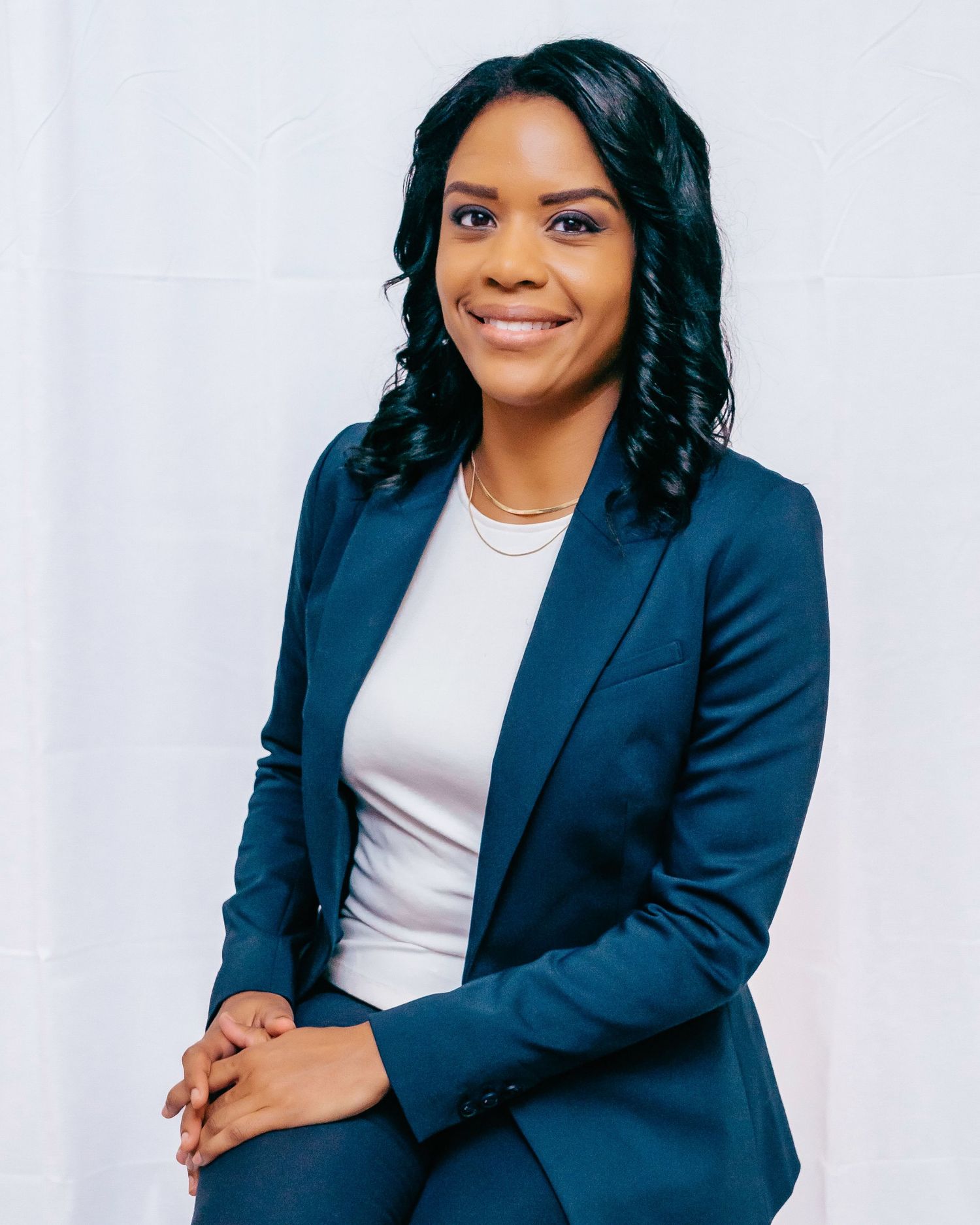 Professional woman in navy blazer and white top poses confidently against white background in studio portraits.