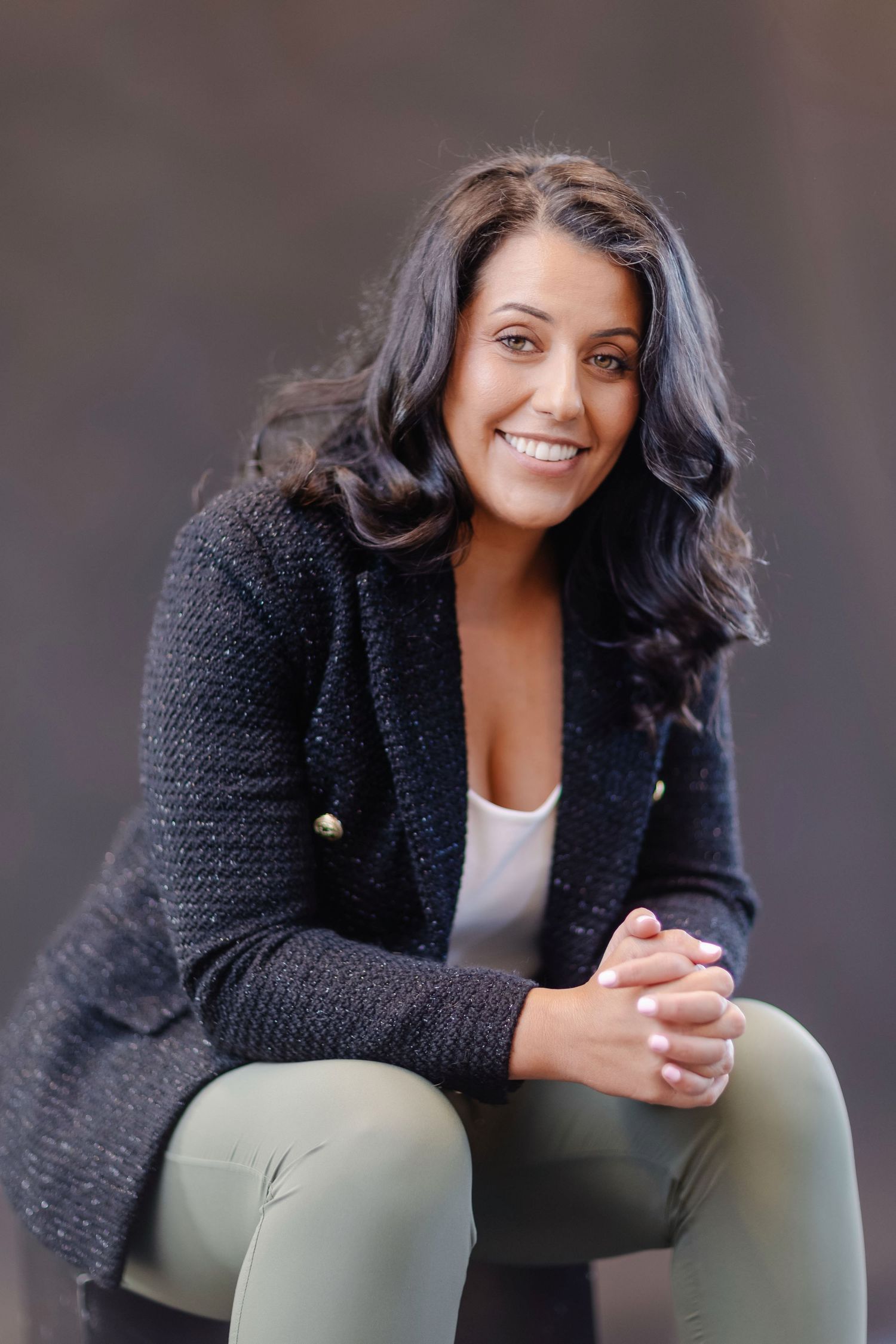 Professional headshot series showing woman in black sweater against blurred background smiling warmly at camera.
