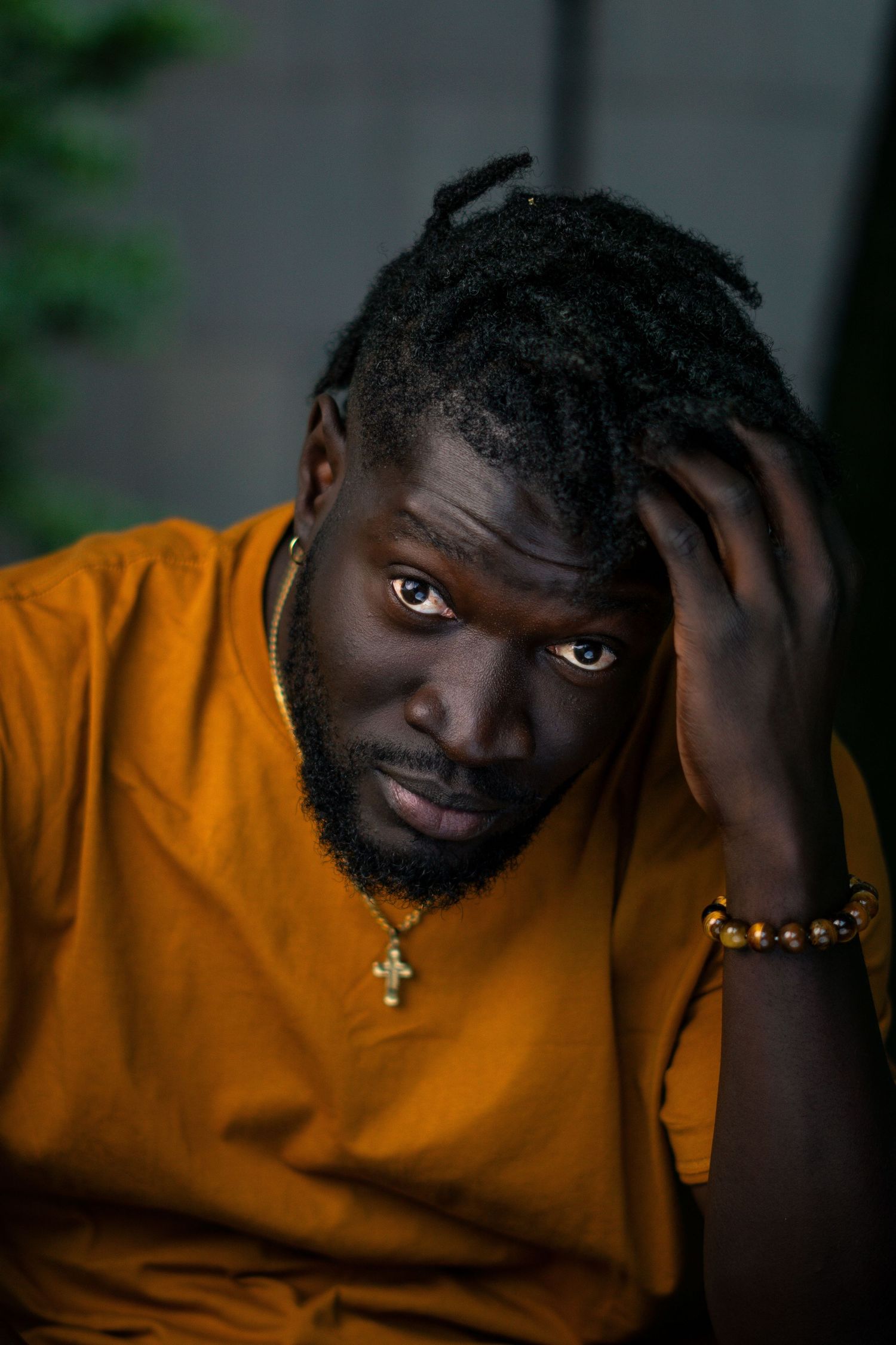 Portrait series of person in orange sweater showing different expressions and poses against dark background.