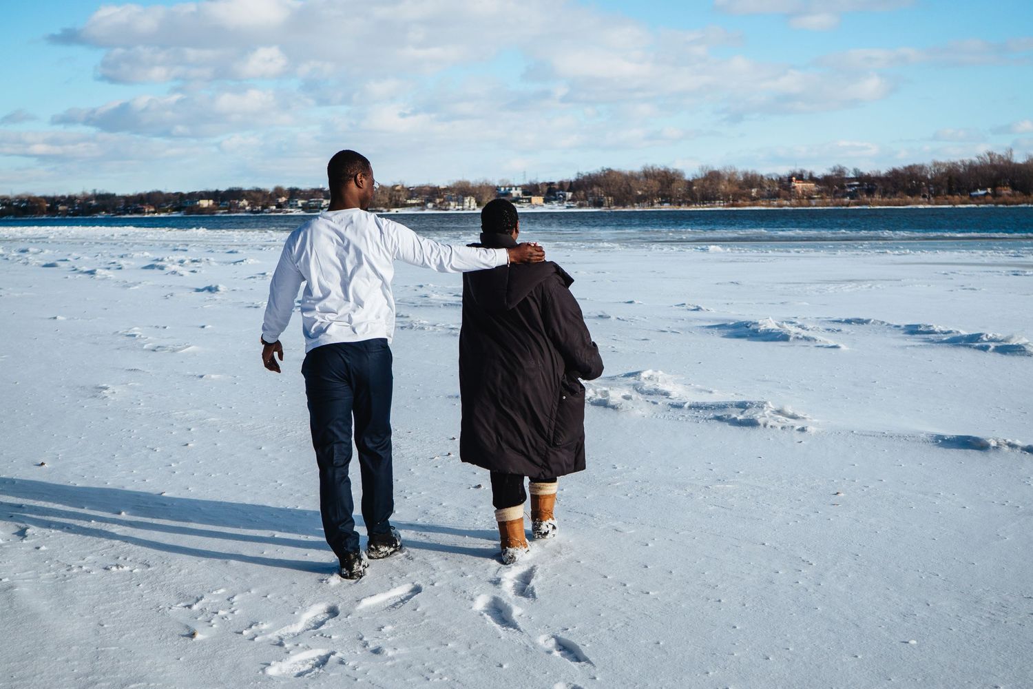 A couple takes a romantic winter walk together across a snow-covered landscape.