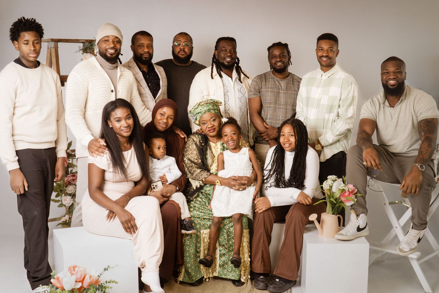 A large family dressed in white and beige poses together for multiple coordinated portrait photos against a light backdrop.