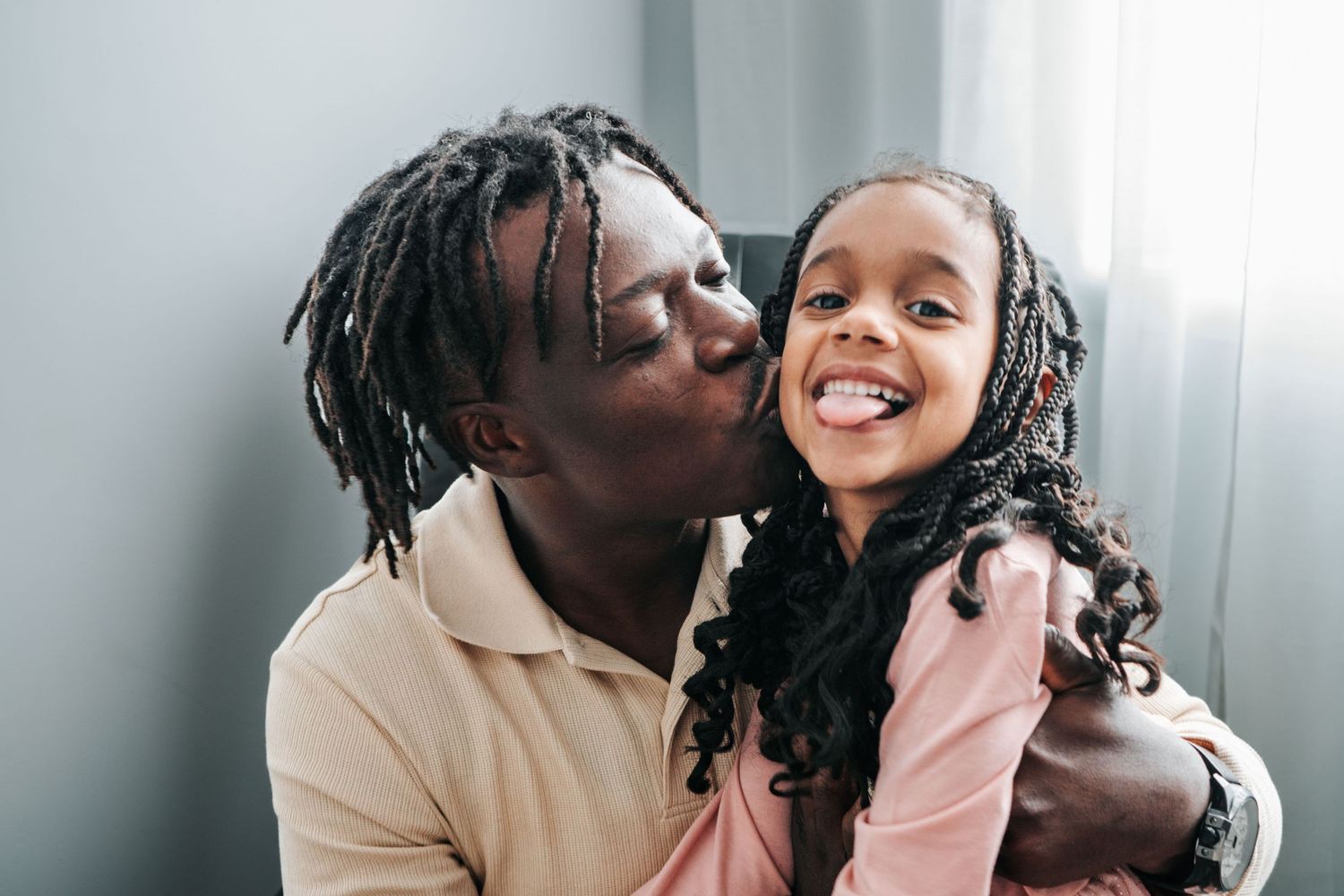 Photo à domicile.
A tender moment of love and laughter shared between parent and child against a gray background.