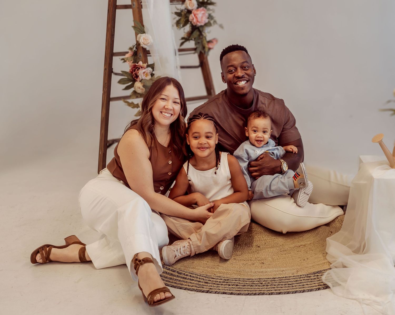 A family relaxing together on a round jute rug during an indoor photoshoot.