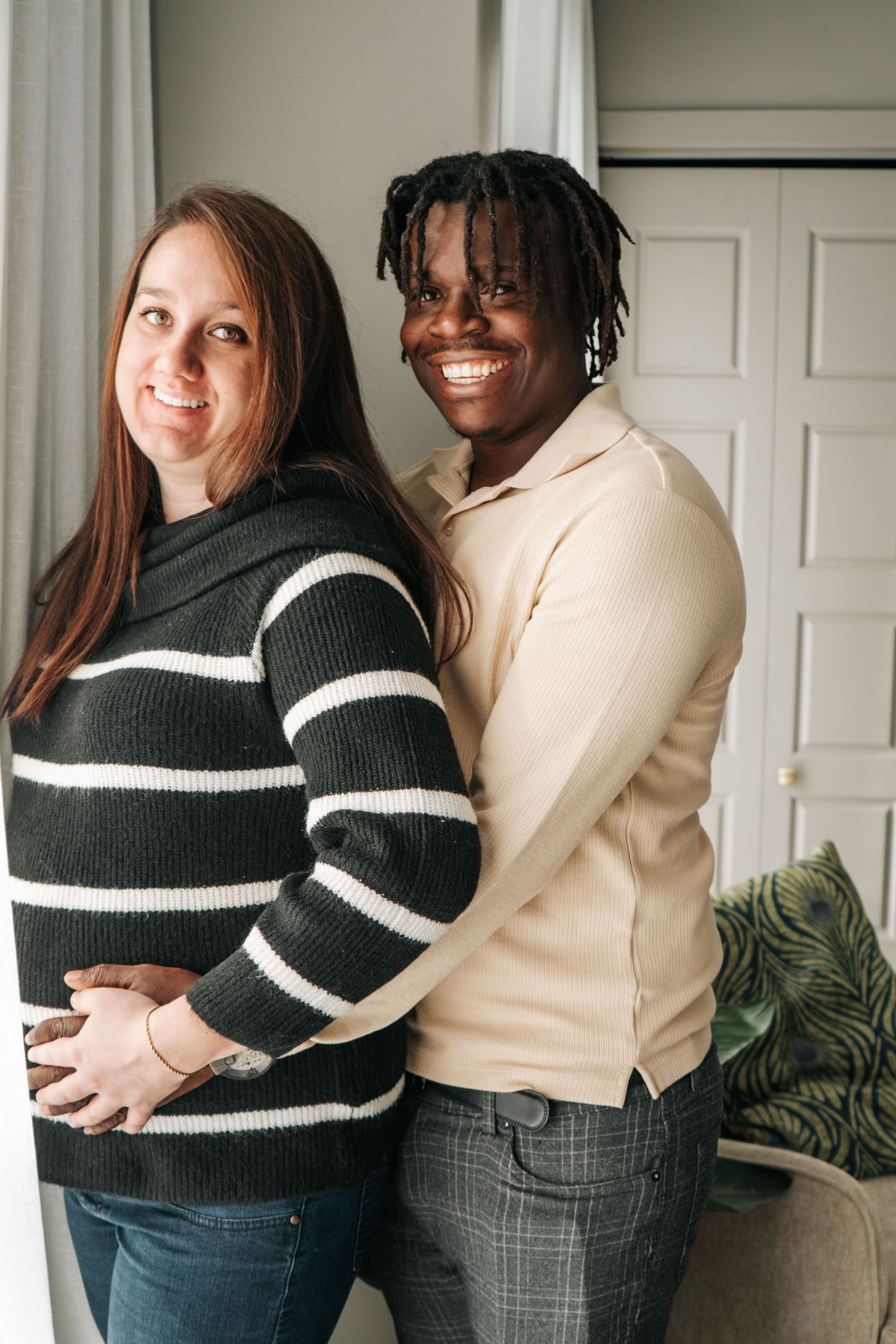 Two friends in coordinating sweaters posing together indoors for casual portraits.