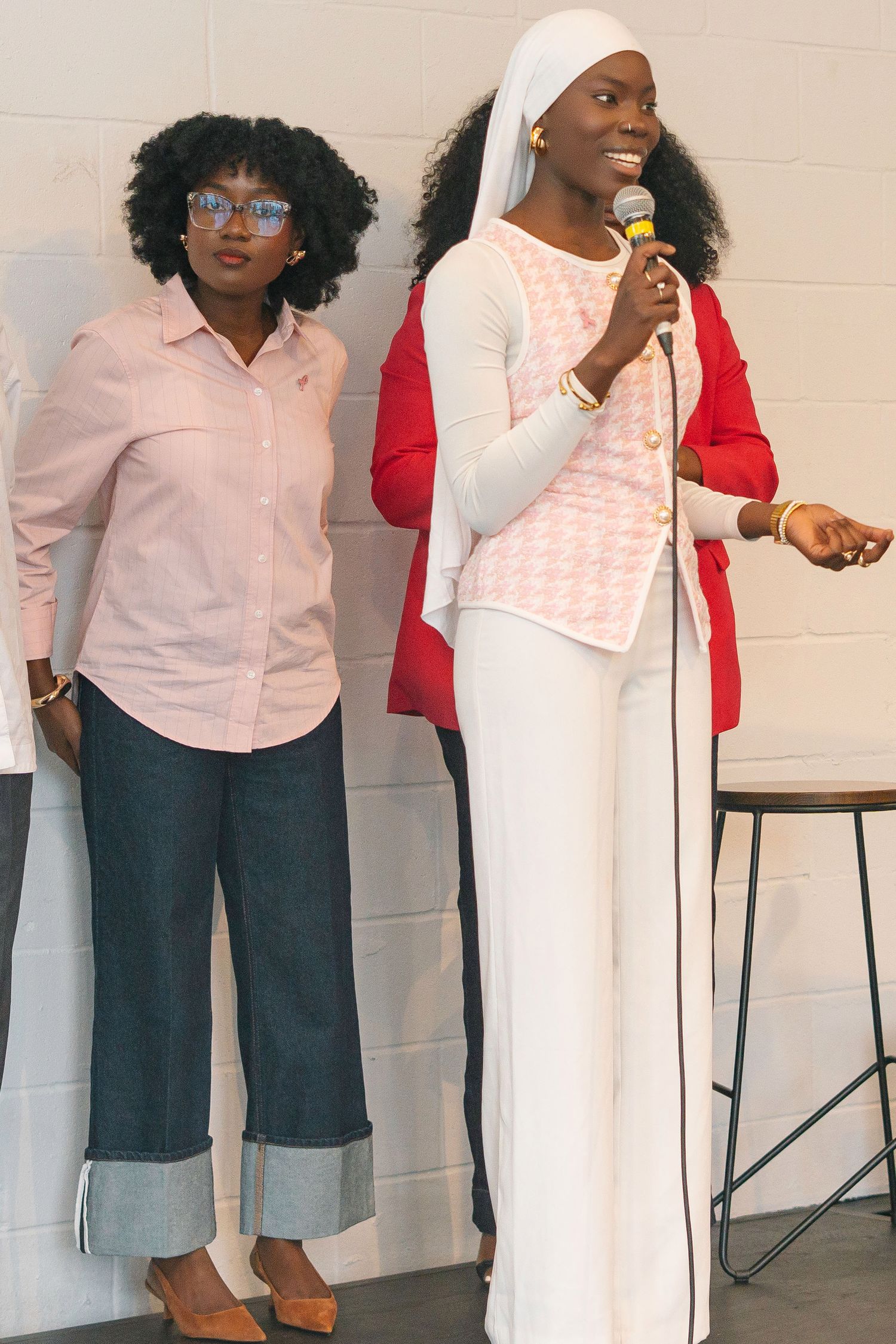 A group of people in white shirts and denim stand together against a light-colored wall.