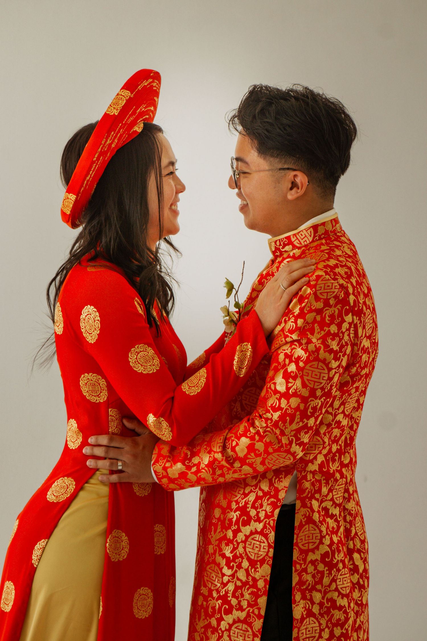A couple wearing traditional red and gold Chinese wedding attire embrace in a romantic photoshoot sequence.