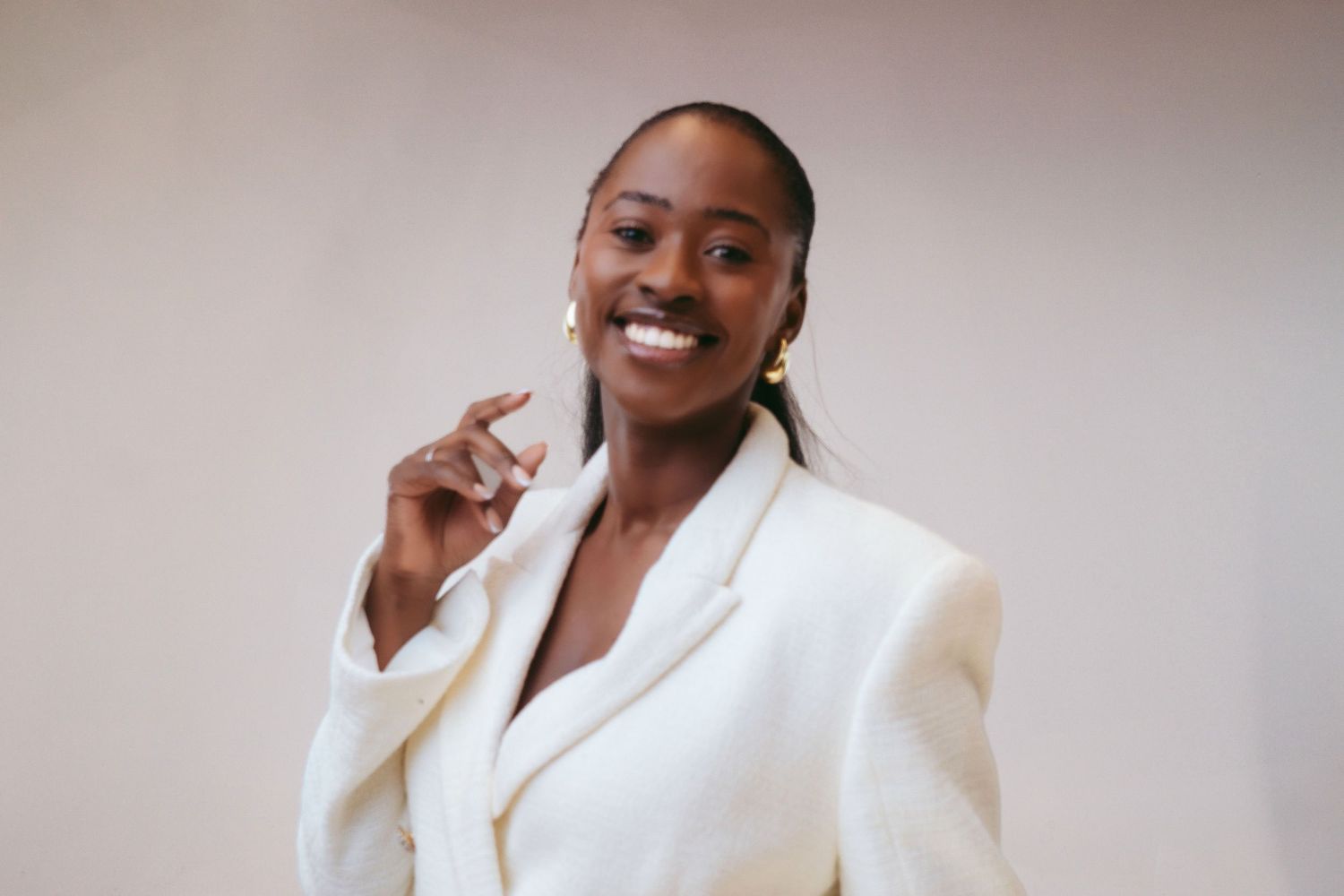 A series of four photos showing someone wearing a stylish white blazer while posing and smiling against a neutral background.