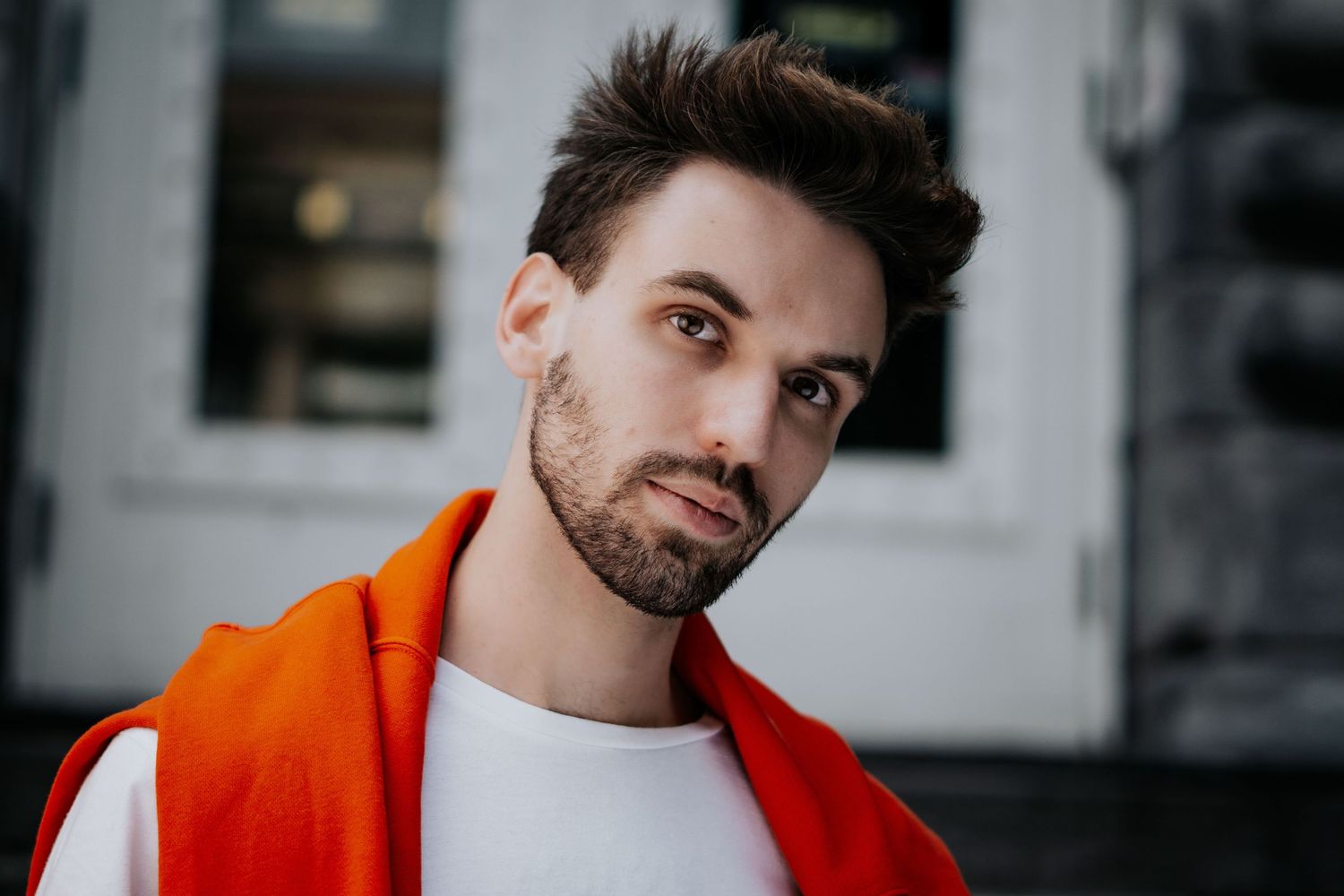 A person in a bright red jacket poses against a blurred urban background in a series of connected photos.