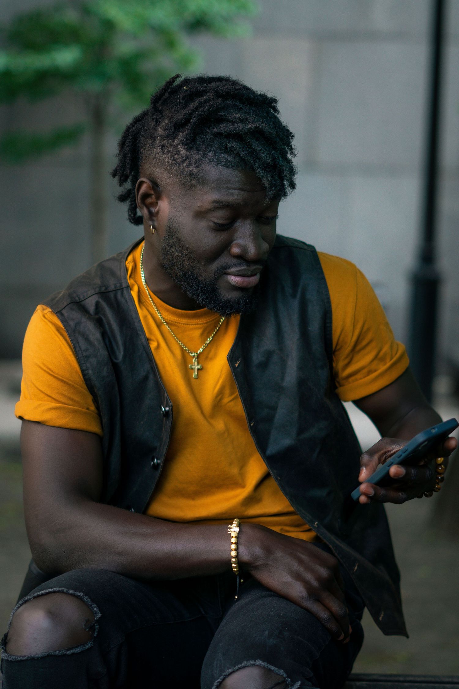 Person in yellow t-shirt and black vest smiles while looking at mobile phone in progressive sequence of shots.