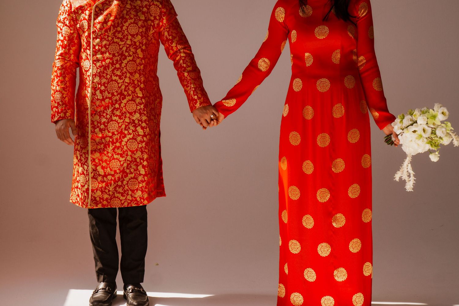 People wearing traditional red and gold outfits in studio photography session.