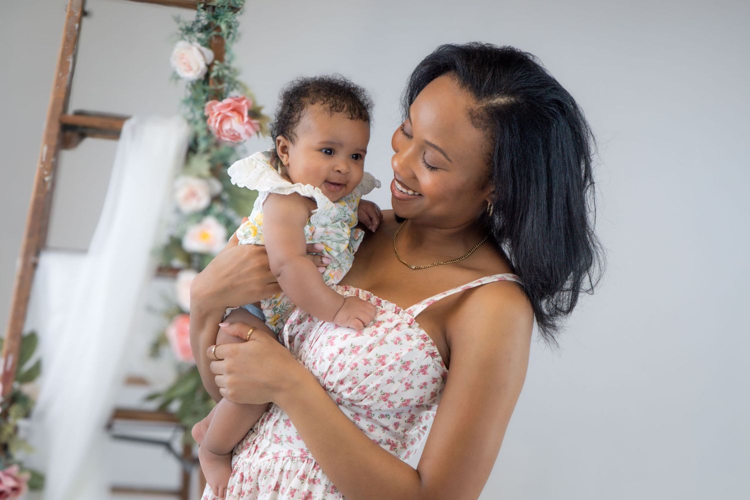 A tender moment between parent and baby with a Christmas tree sparkling in the background.