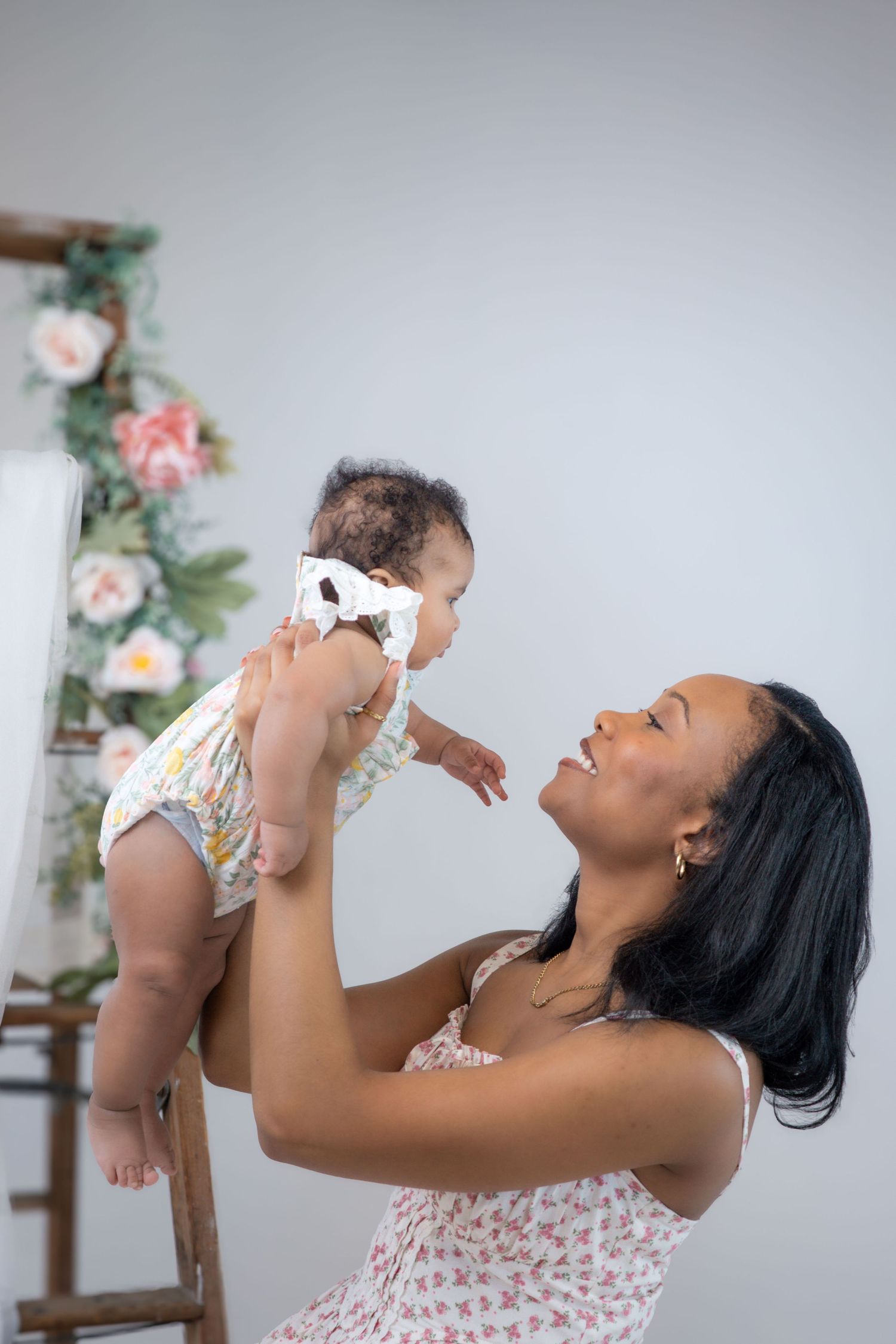 A joyful moment captured in a series of photos showing someone lifting a baby while wearing a floral dress.