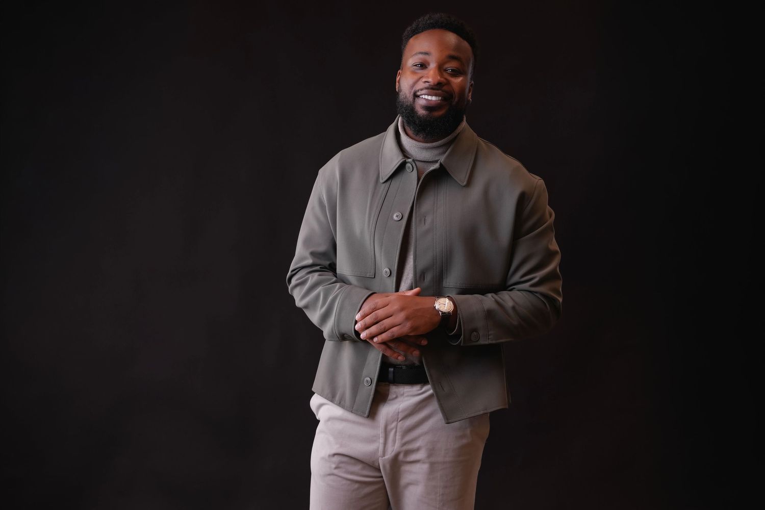 A person in a gray suit jacket and light pants poses in a series of professional headshots against a dark background.