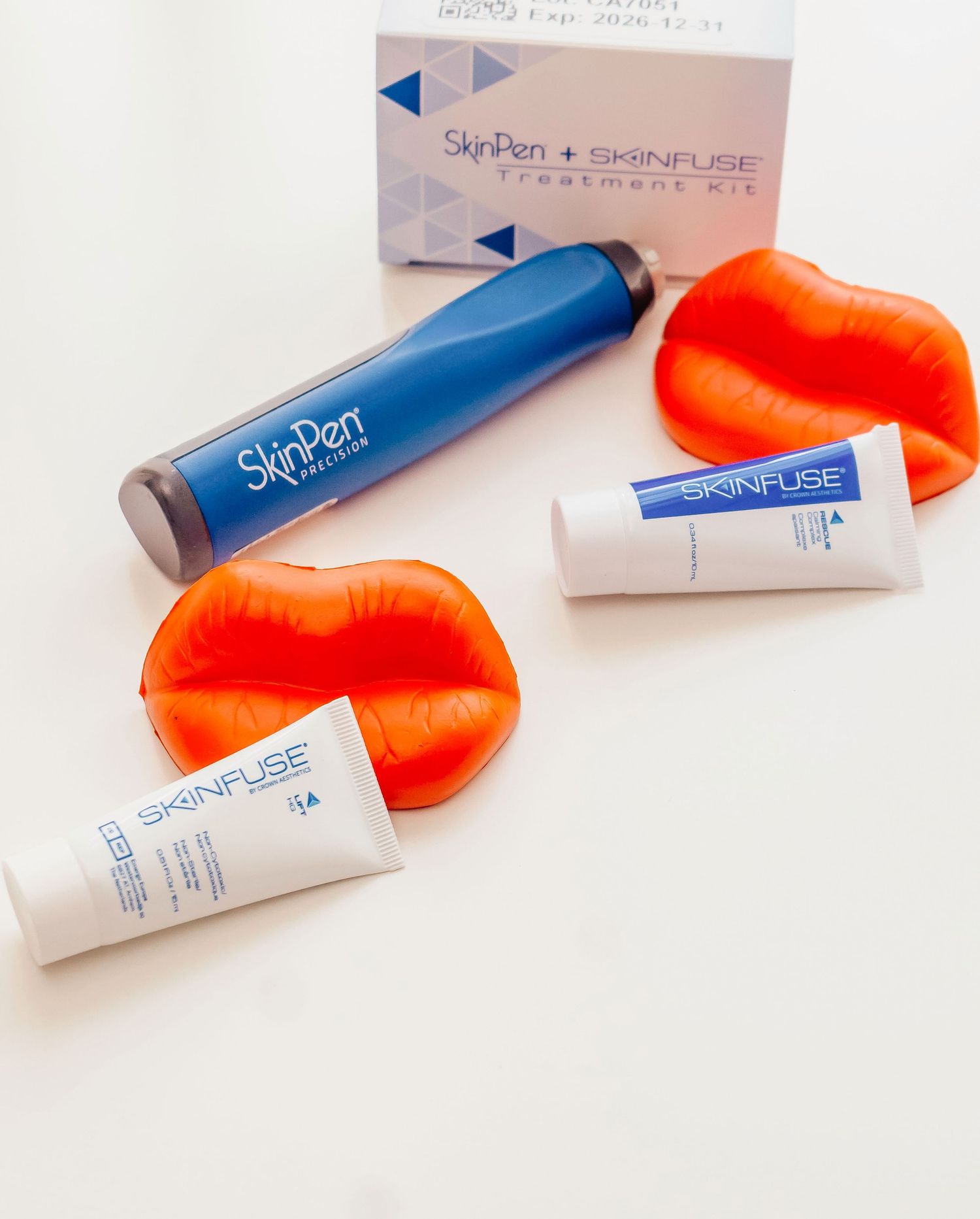 Orange lipstick tubes and SkinPen Skinluxe beauty products arranged on a white background.