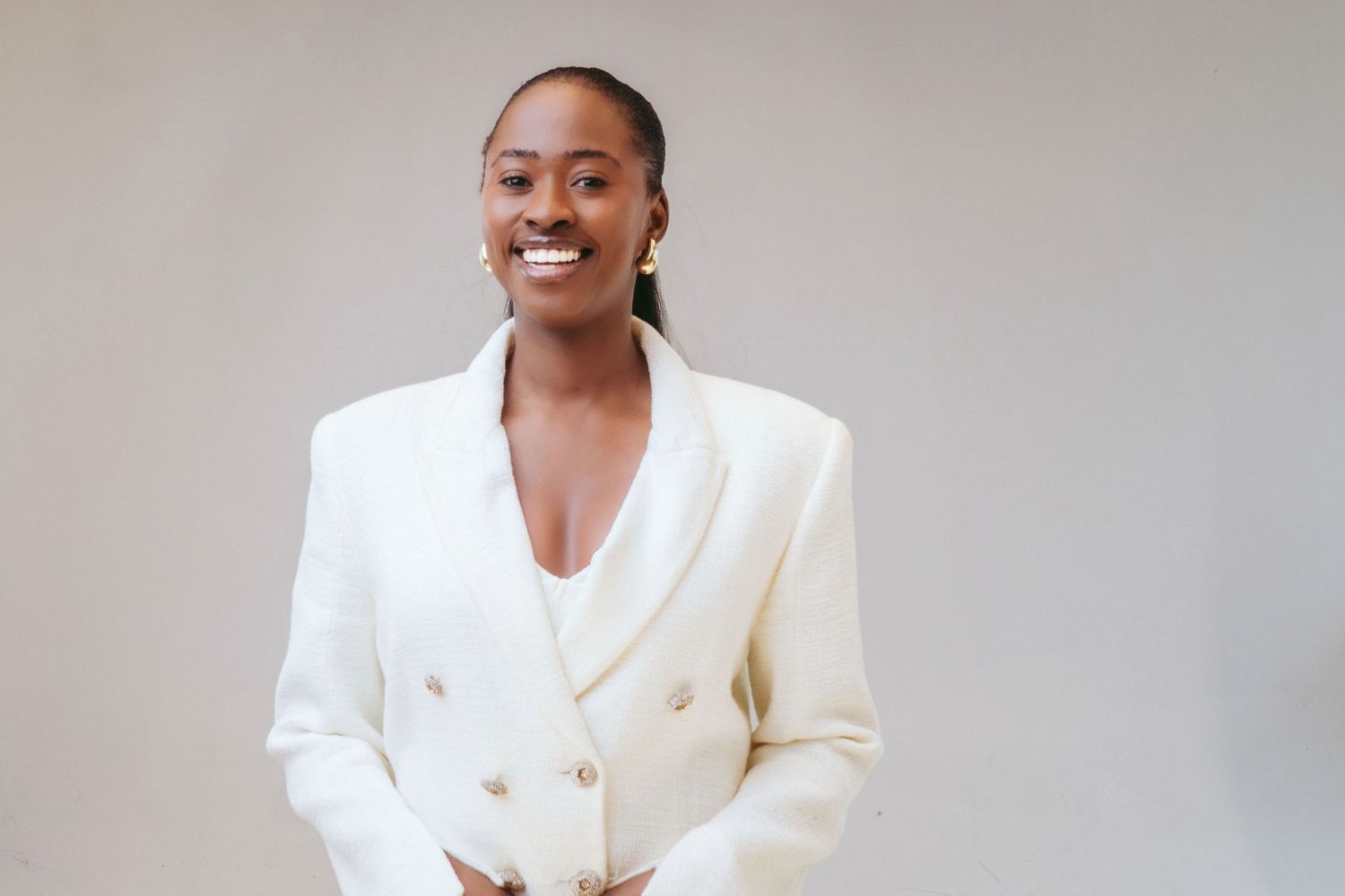 Professional portrait of someone wearing a crisp white double-breasted blazer while smiling warmly against a neutral background.