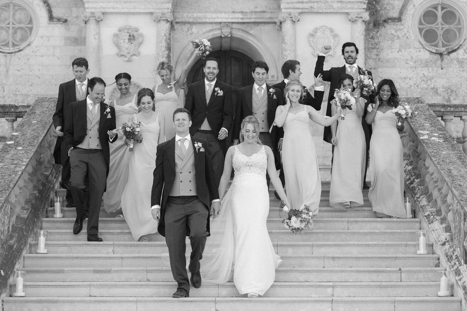 Four black and white photographs showing a wedding party exiting a grand church and walking down stone steps.