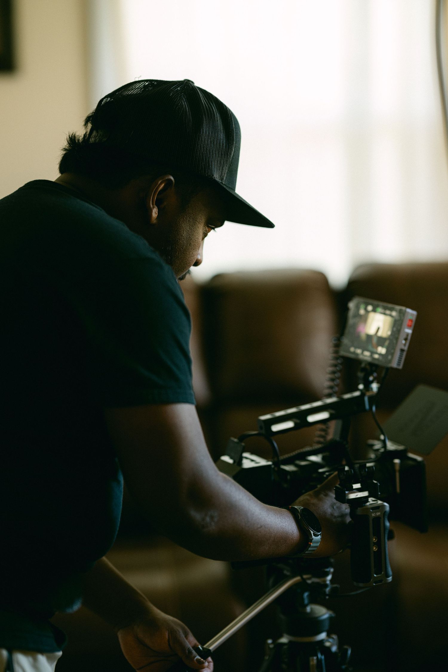 Videographer works with professional camera equipment in low-light setting.