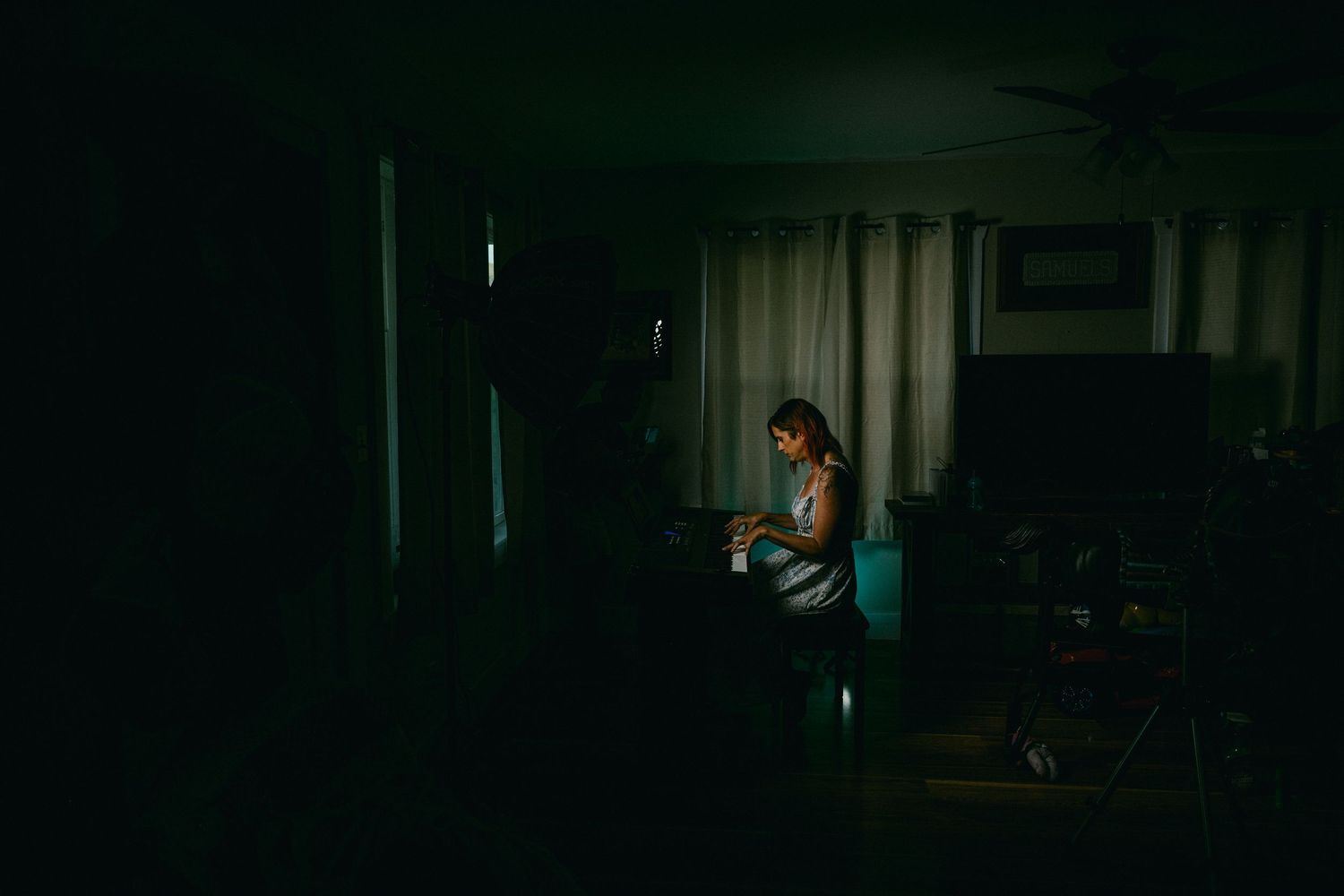 Person playing piano in a dark room with atmospheric lighting.