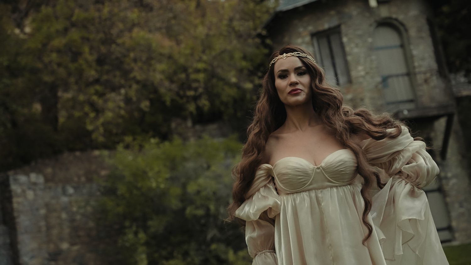 A romantic outdoor photoshoot features someone in a flowing white dress walking through a misty forest setting.
