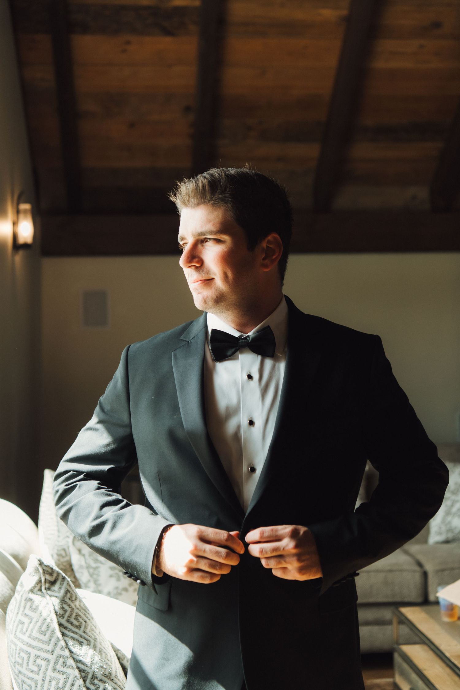 Classic formal portrait in black tuxedo with dramatic window lighting.