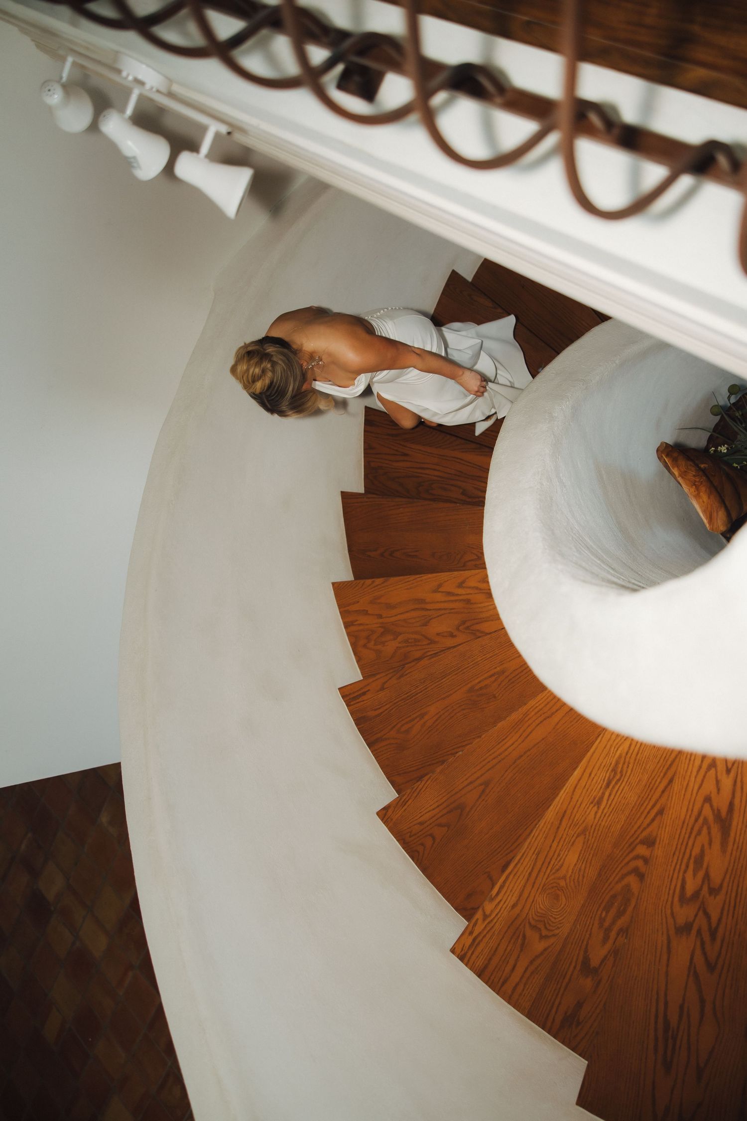 Close-up view of a curved wooden spiral staircase with white walls and polished hardwood steps.