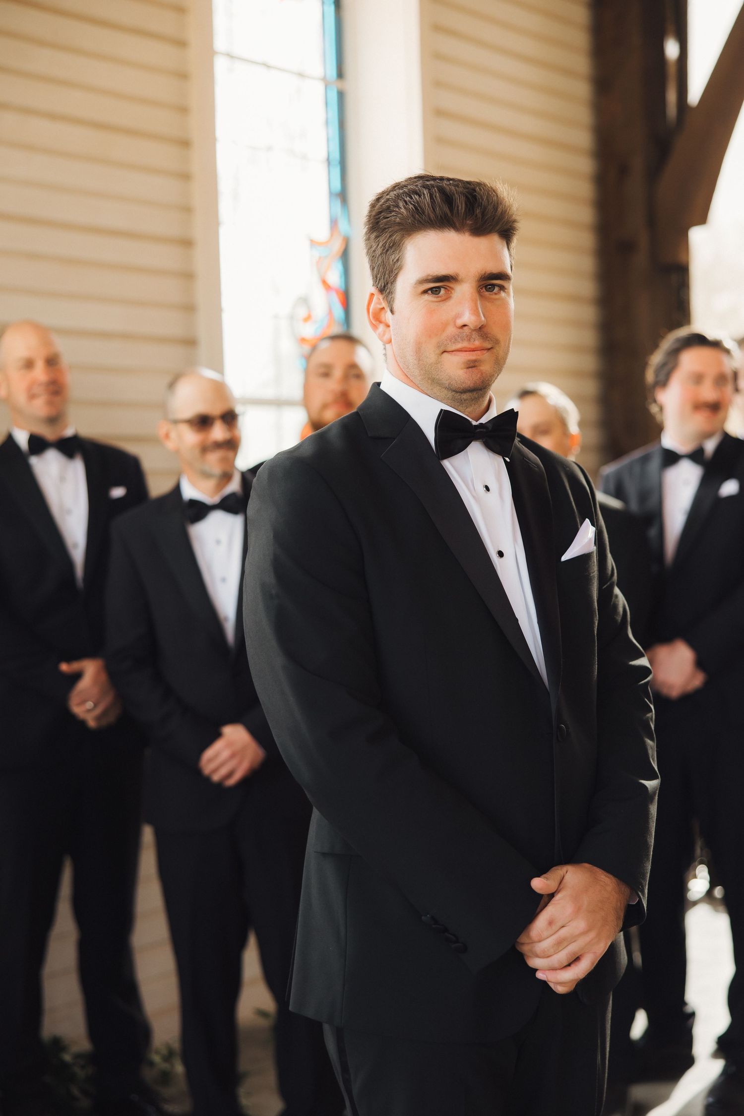 A group of formally dressed men in black tuxedos and bow ties stand together at a formal event.