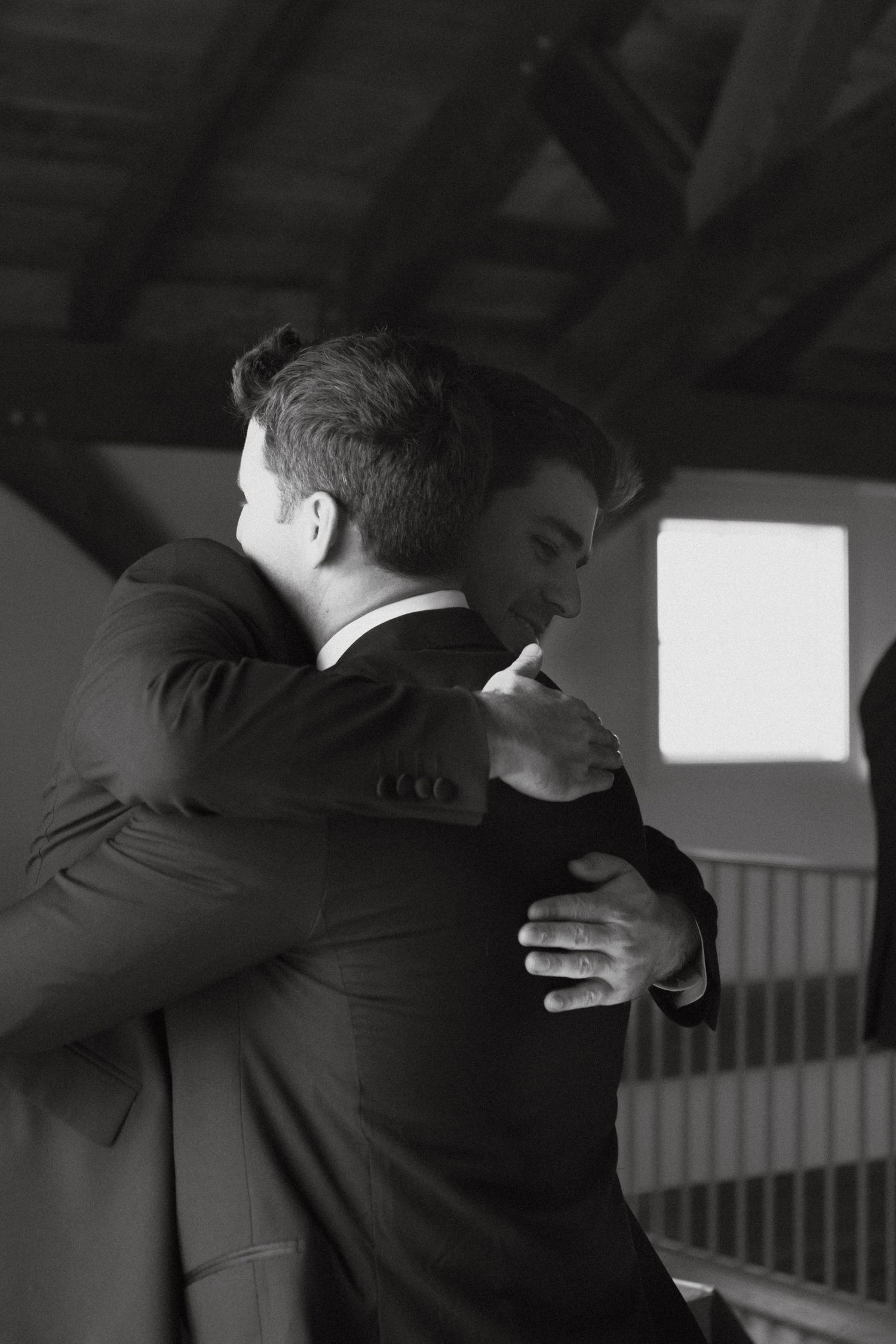 Emotional embrace between two people in formal suits.