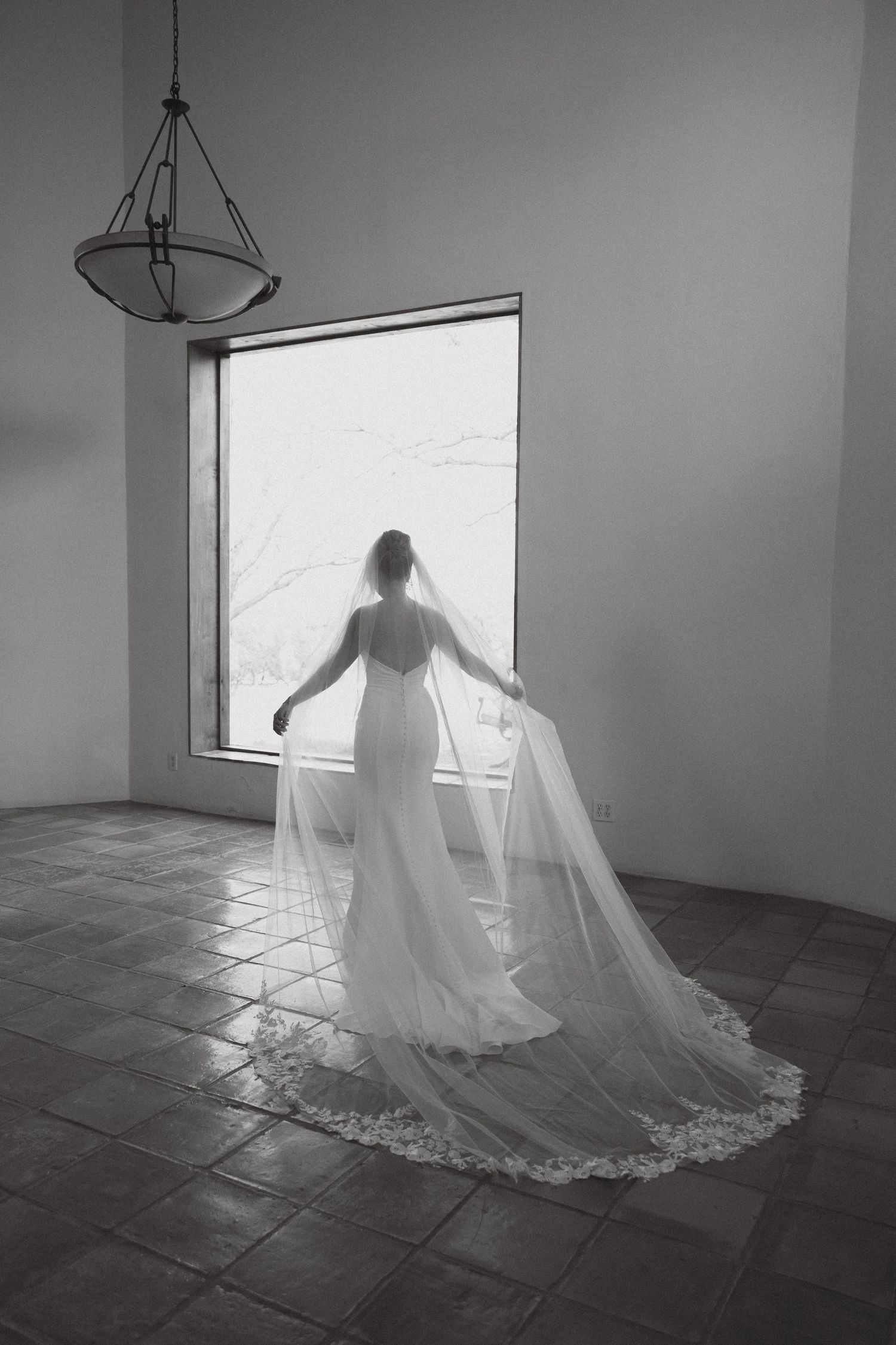 Artistic black and white series of a wedding dress silhouette against bright window light.