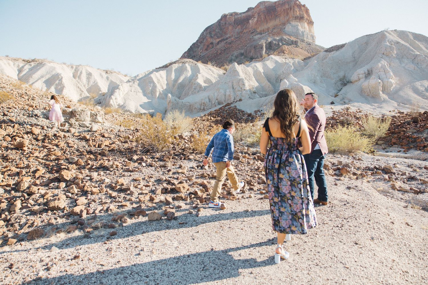 People walking on a desert trail with red rocks and mountains in the background at Red Rock Canyon.
