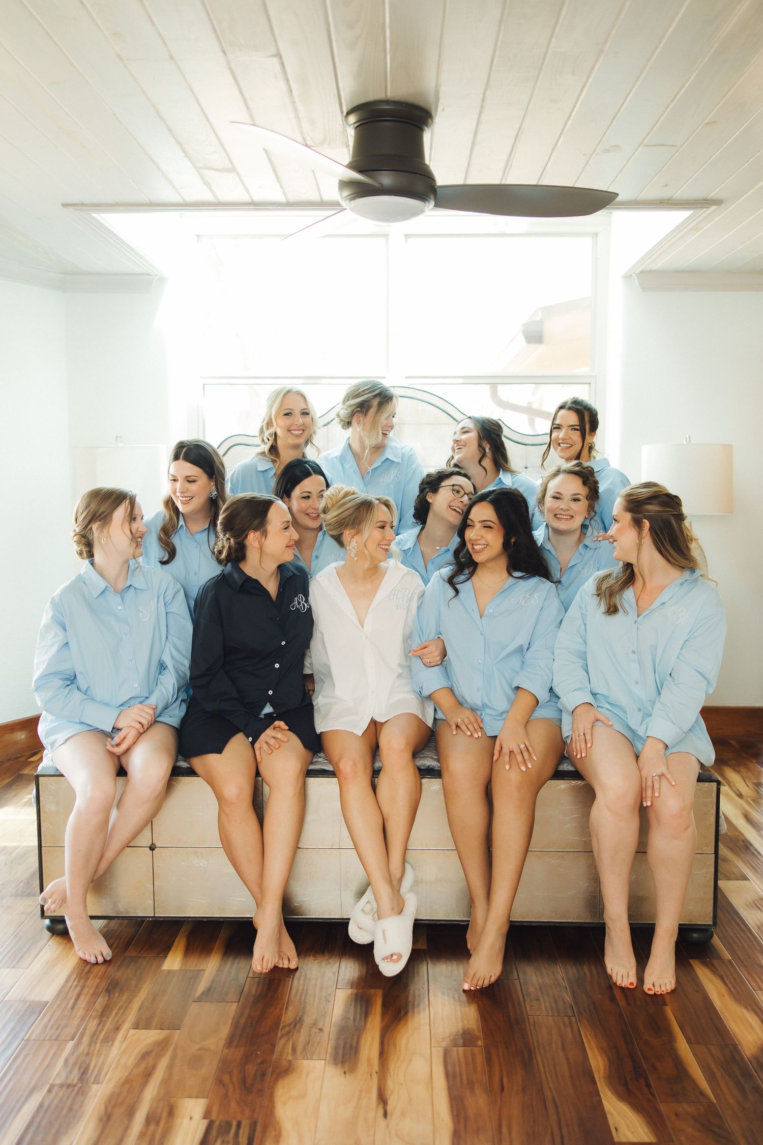 Wedding party members wearing light blue shirts sitting in a row showing off their bare feet.