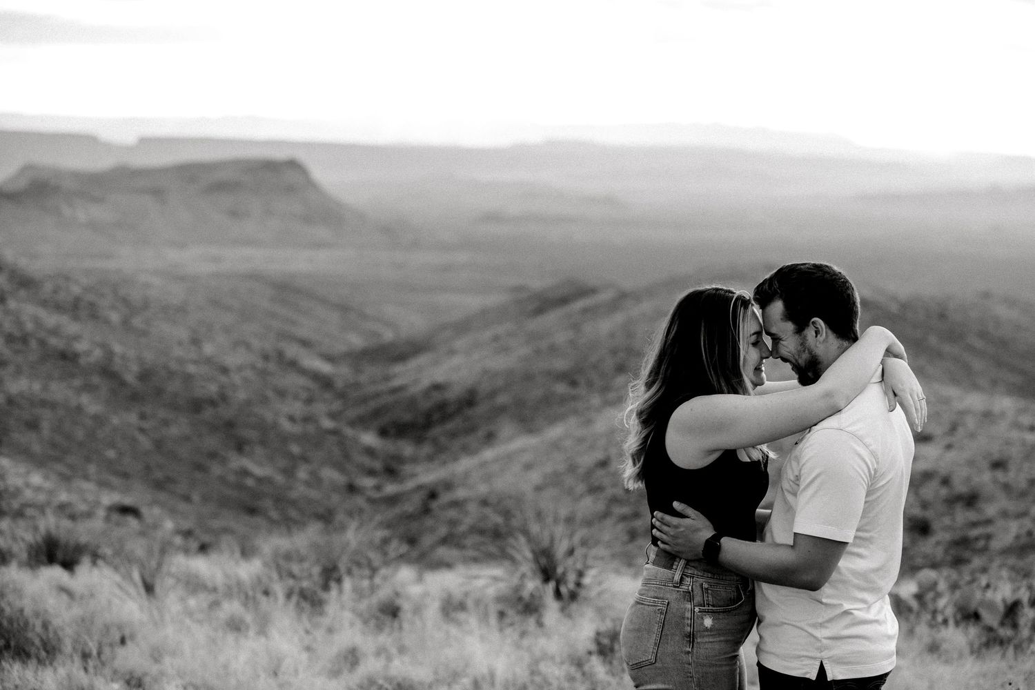 Black and white film strip showing a romantic outdoor mountain scene with a couple embracing in nature.