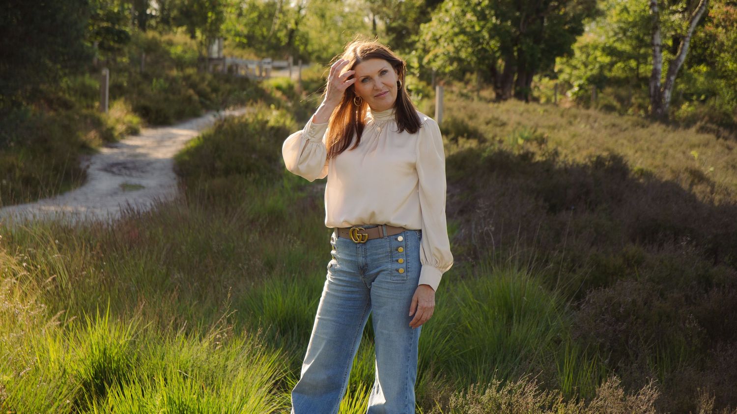 Brunette woman standing in nature and smiling. In the Teut in Zonhoven creating a serene and calm vibe.