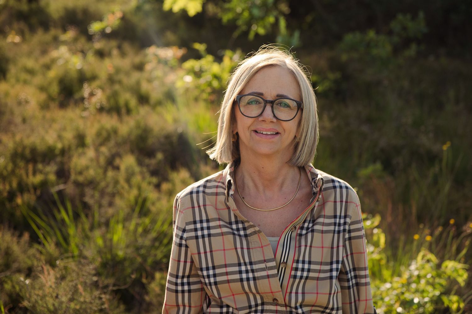 Middle aged woman standing in nature and smiling. In de Teut in Zonhoven.