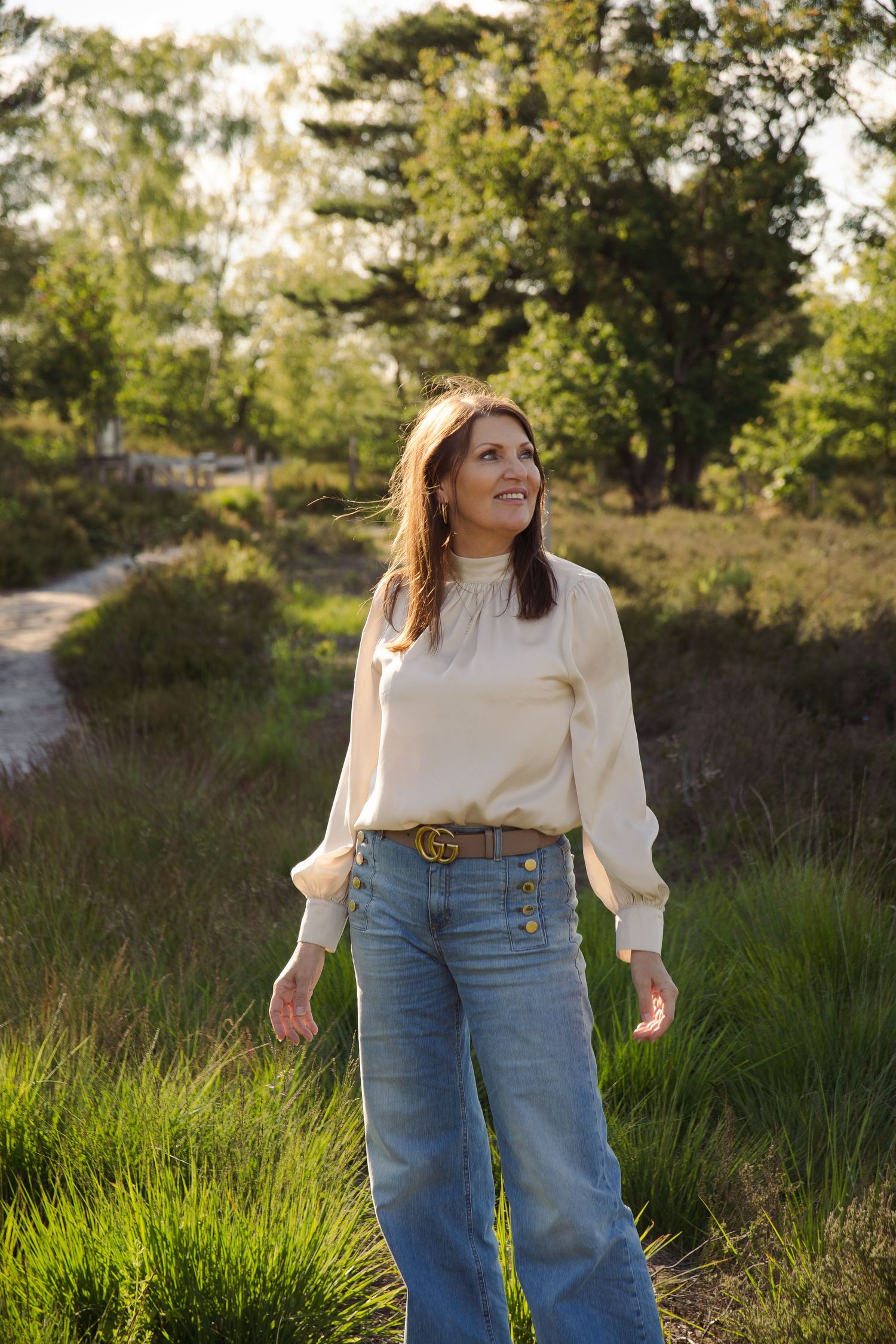 Brunette woman standing in nature and smiling. In the Teut in Zonhoven creating a serene and calm vibe.