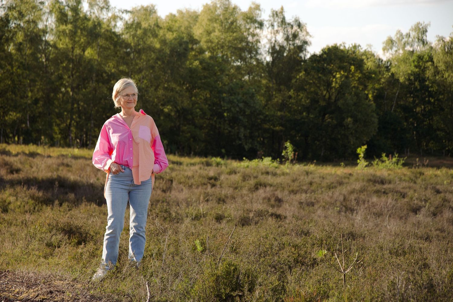 Blonde middle aged woman gazing far away in nature and smiling. In the Teut in Zonhoven creating a serene and calm vibe.