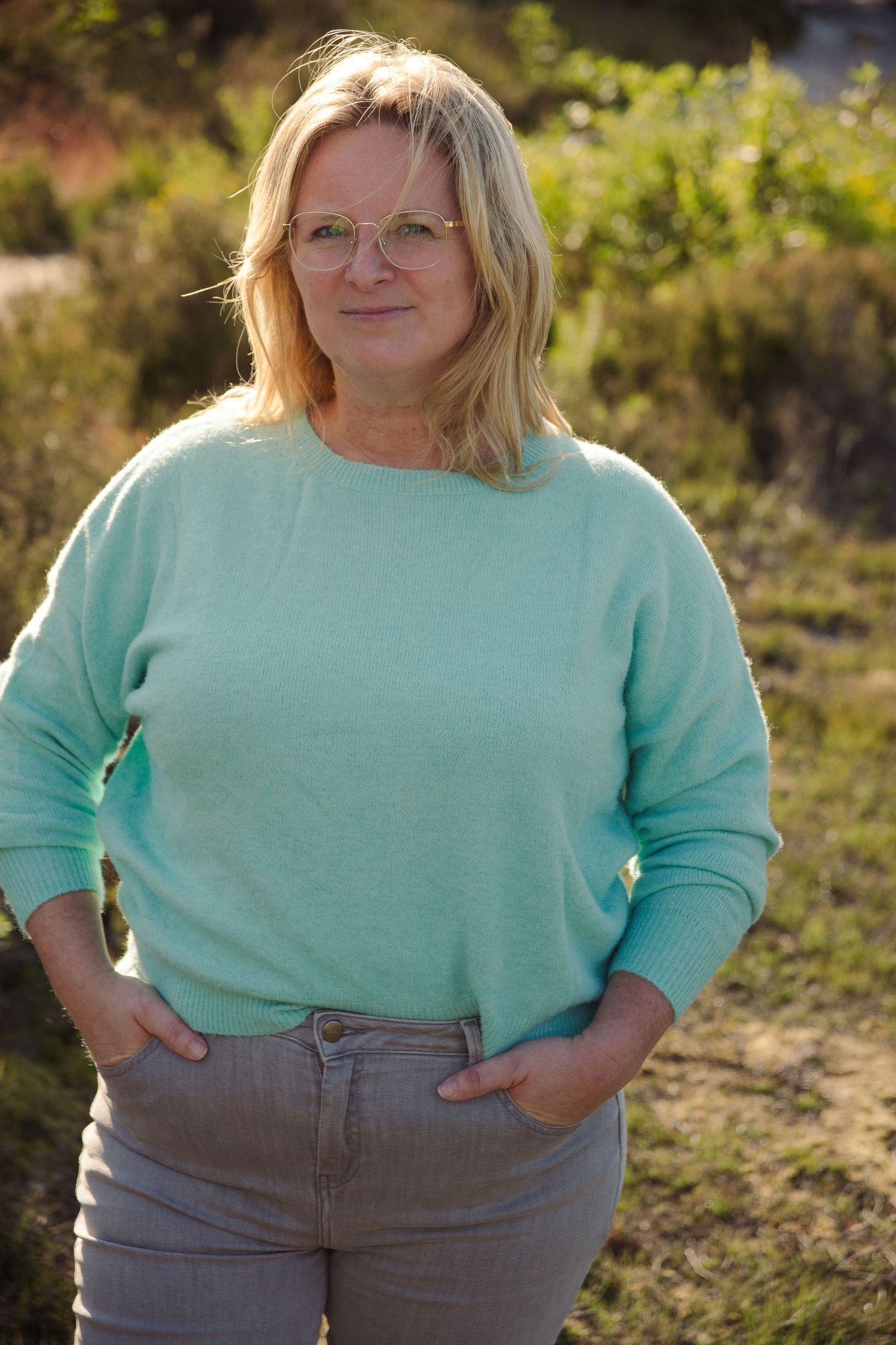 Middle aged woman standing in nature and smiling in the camera. In de Teut in Zonhoven.