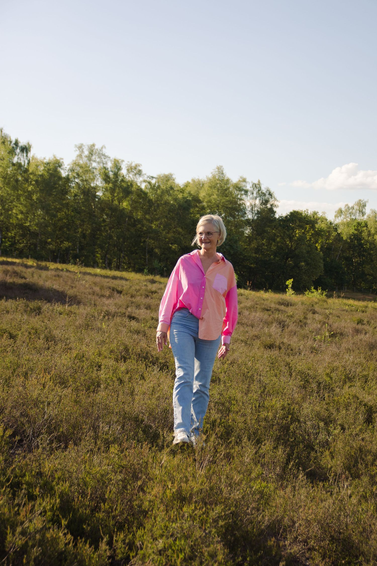 Middle aged woman walking through the grass in de Teut in Zonhoven.